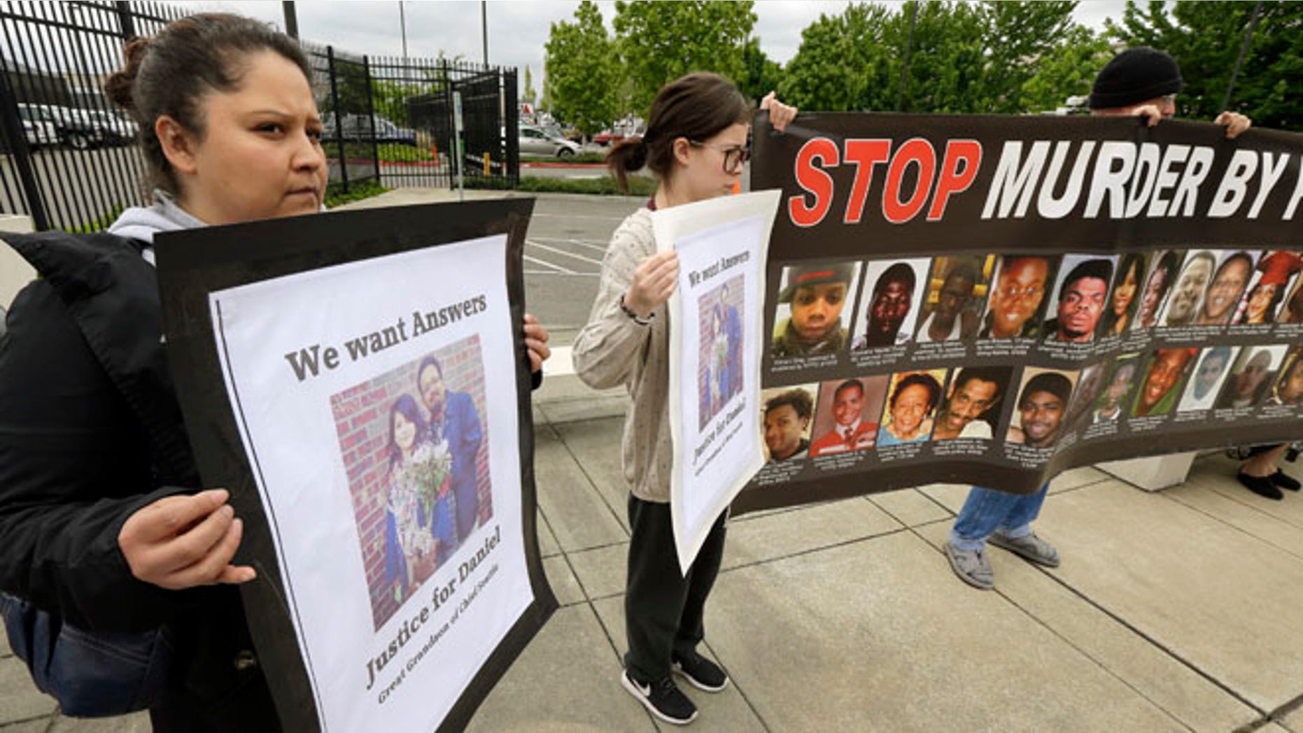 Lanna Covarrubias, left, the sister of Daniel Covarrubias, holds a sign Monday, May 11, 2015, as she stands with supporters outside police headquarters in Lakewood, Wash. The interim police chief in Lakewood says officers shot and killed Daniel Covarrubias in a lumber yard last month because he pointed a cell phone at them as though it were a gun. (AP Photo/Ted S. Warren)