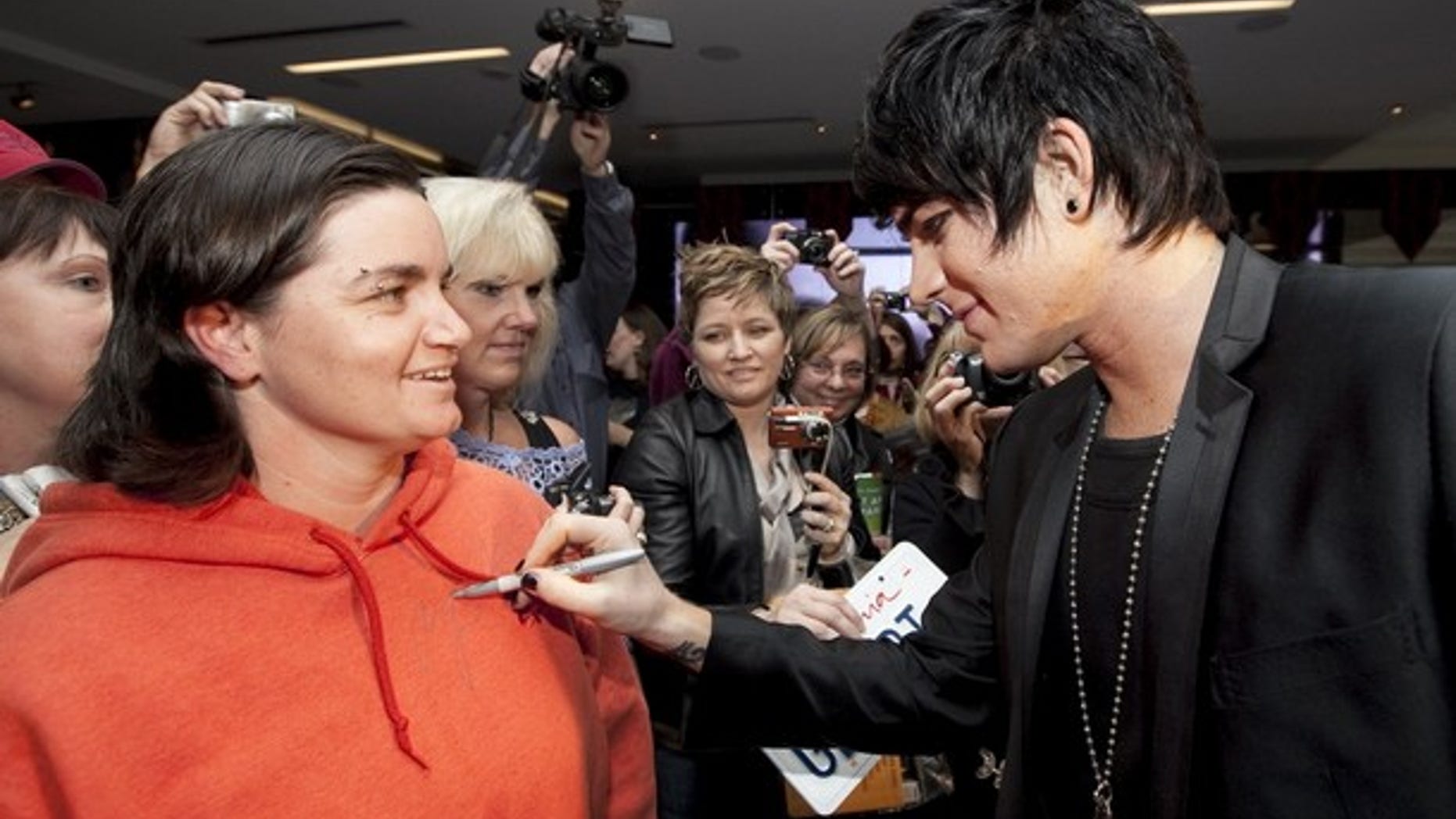 Singer Adam Lambert autographs a fan's sweatshirt.