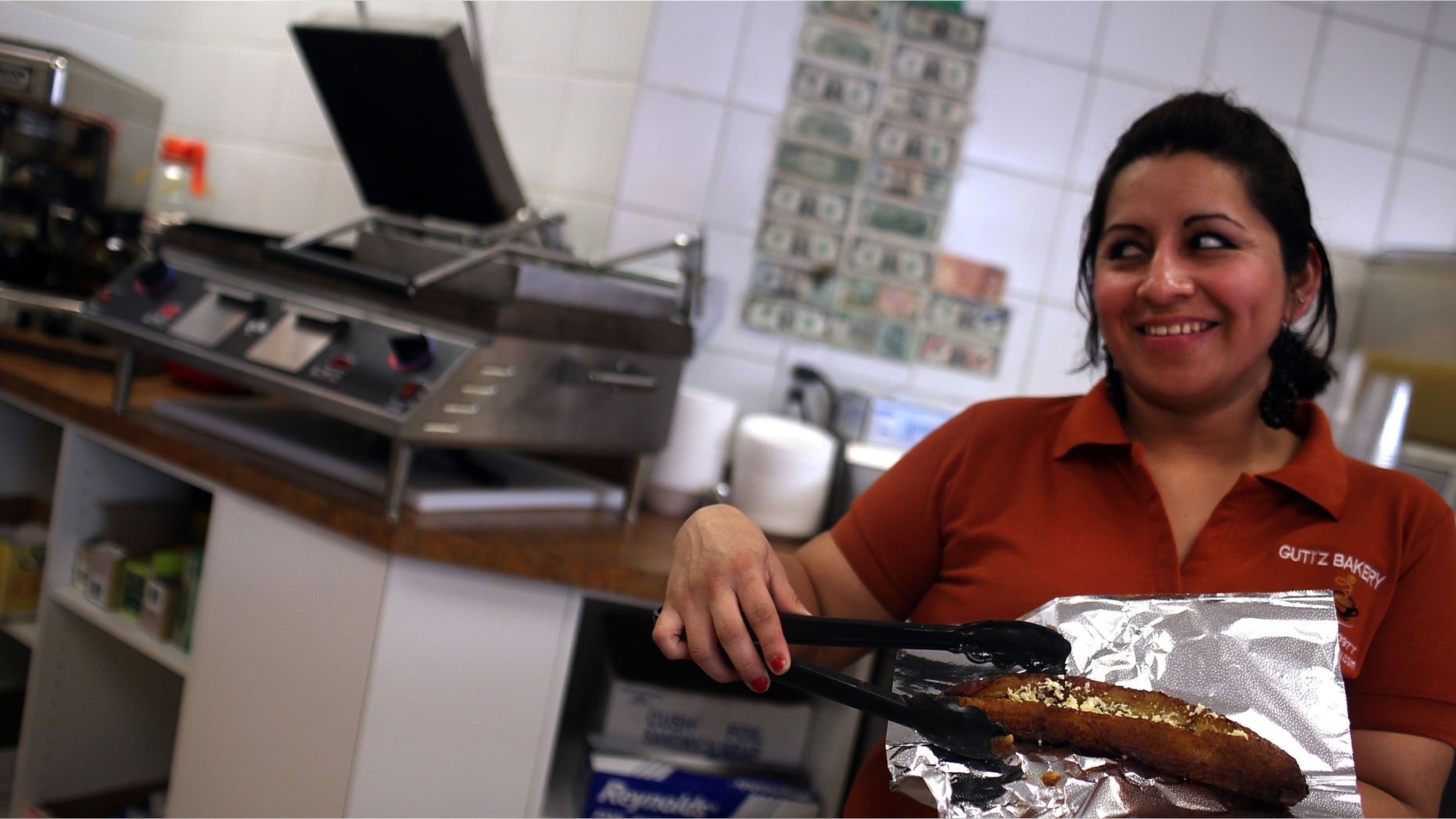 EAST HAVEN, CT - FEBRUARY 01: A waitress at Guti'z Bakery displays traditional Ecuadorian food on February 1, 2012 in East Haven, Connecticut. Following an investigation by the FBI, four East Haven police officers were arrested last week and accused of abusing Latinos in the working class community of 28,000 people which was nearly predominately white a generation ago. The case comes after a long and continuing FBI investigation where more arrests are expected. A recent civil rights investigation which was released last month revealed a pattern of discriminatory policing in East Haven and the town has been warned by the U.S. Justice Department to make reforms. The arrested officers have been accused of subjecting Hispanics to beatings and false arrests among other things. Currently East Haven's Latino population is around 10 percent. (Photo by Spencer Platt/Getty Images)