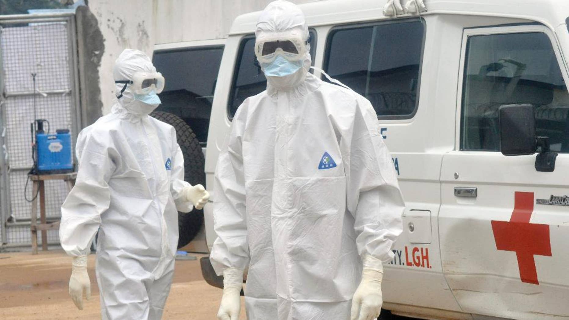 Health workers wearing protective gear wait to carry the body of a person suspected to have died from Ebola, in Monrovia, Liberia, Monday Oct. 13, 2014. (AP Photo/Abbas Dulleh)