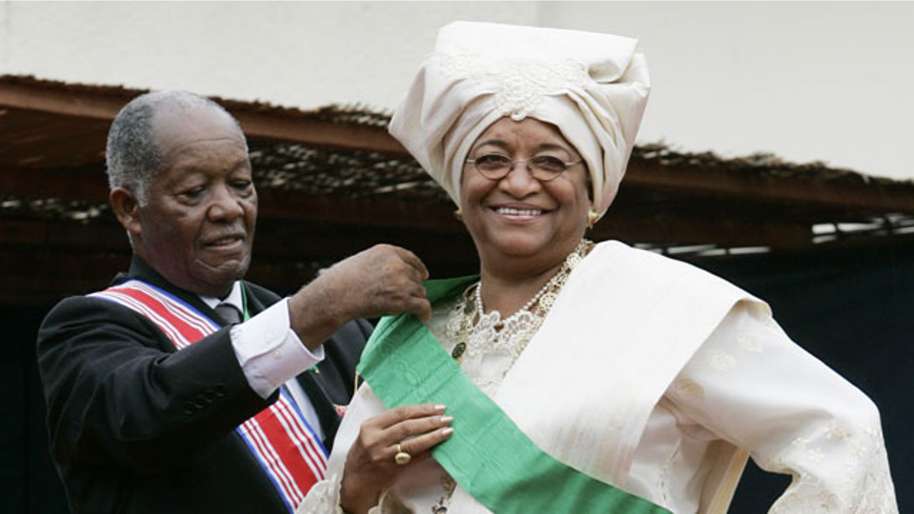 FILE - In this Jan. 16, 2006 file photo, Liberia's new President Ellen Johnson Sirleaf, right, is helped with a sash by Liberian Senior Ambassador-at-large George W. Wallace, Jr., during her inauguration at the Capitol Building in Monrovia, Liberia.