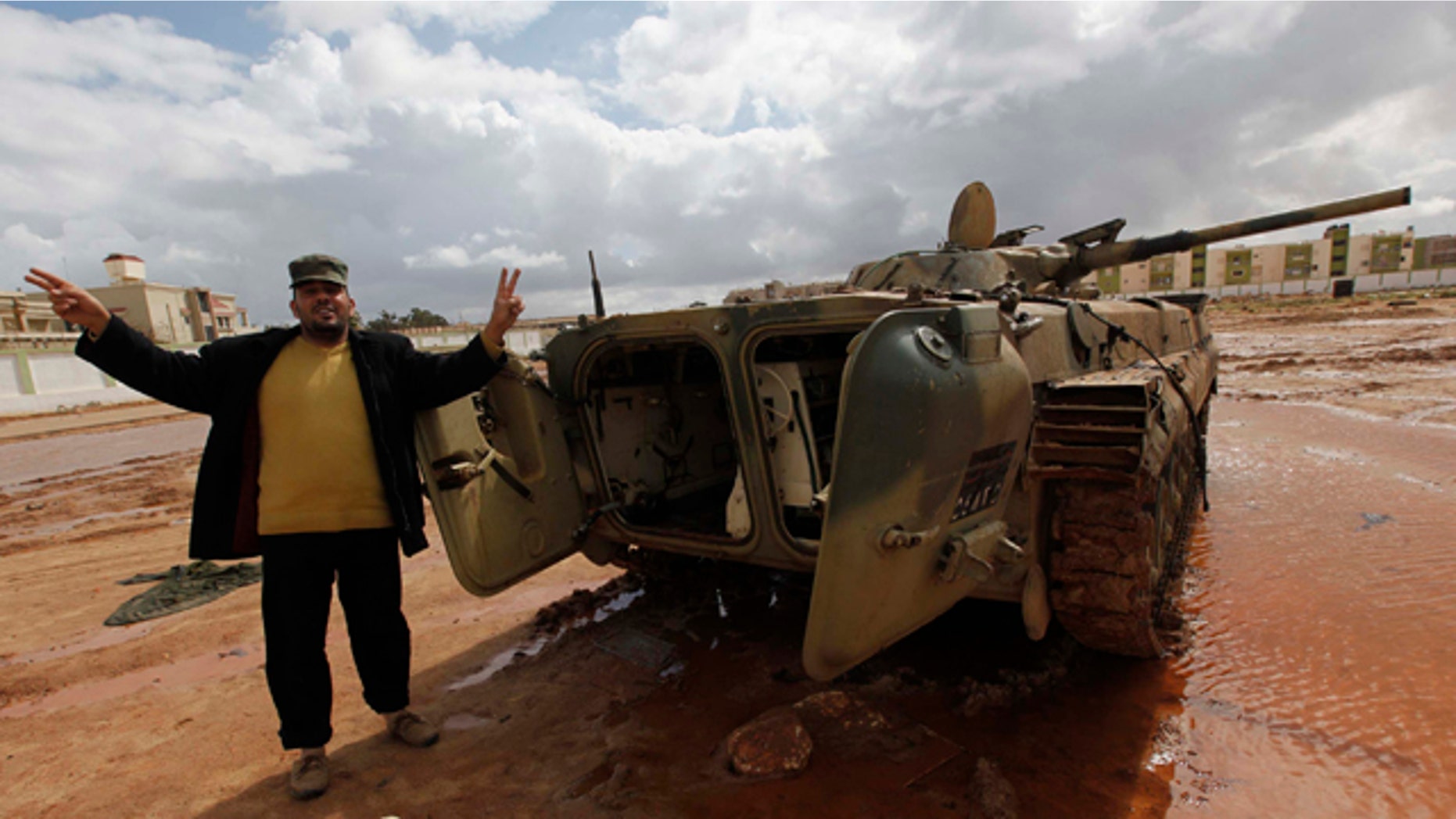 Feb. 24, 2011: A Libyan man flashes a V sign next to a destroyed tank at Al-Katiba military base after it fell to anti-Libyan leader Moammar Gadhafi protesters a few days ago