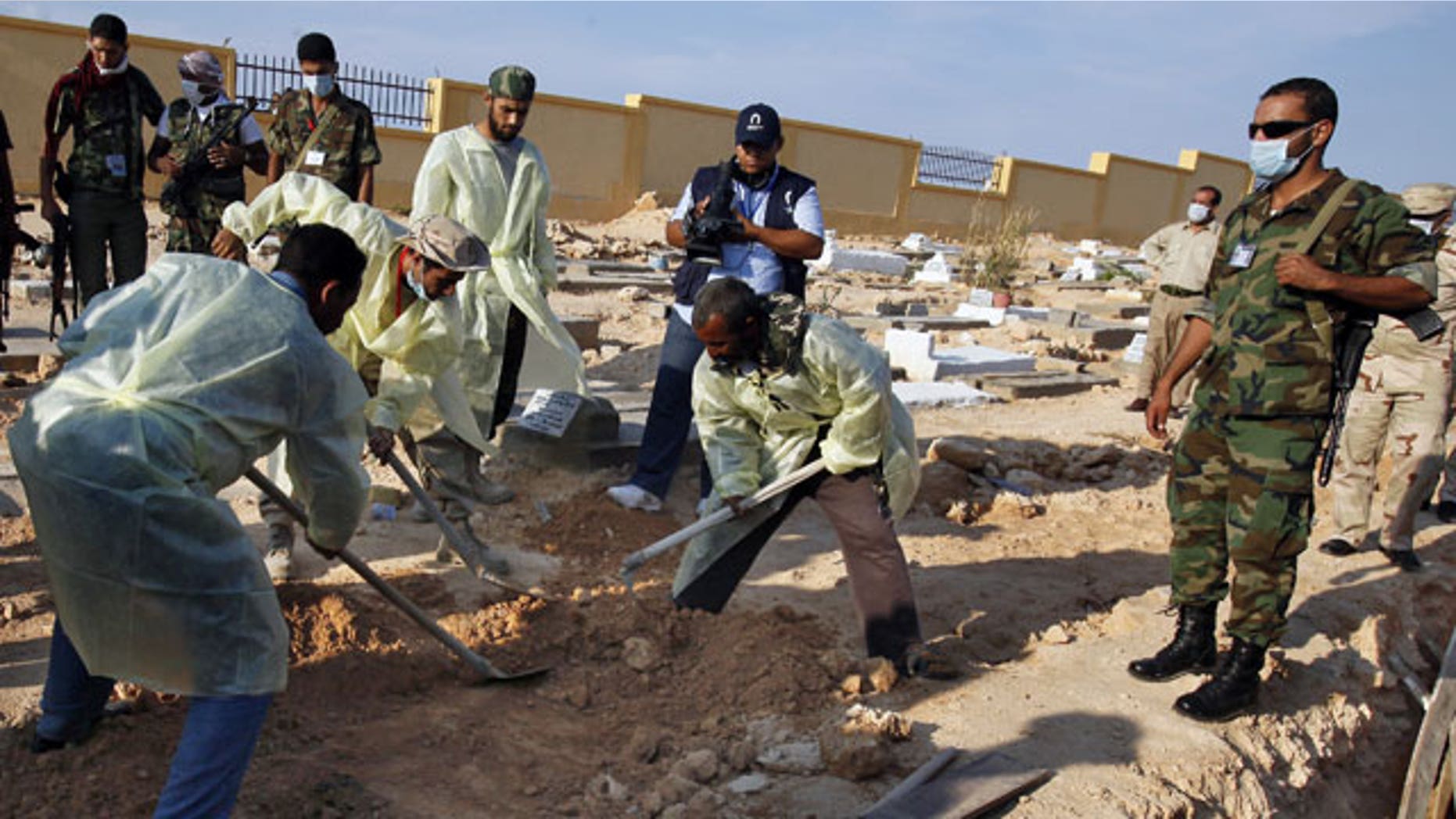 Libyan medical team and revolutionary fighters dig at a mass grave in Gargarish, on the coast some four miles, from the center of Tripoli, Libya, containing the bodies of more than 200 people who were killed in the chaos surrounding the rebel assault that ousted Muammar Qaddafi.