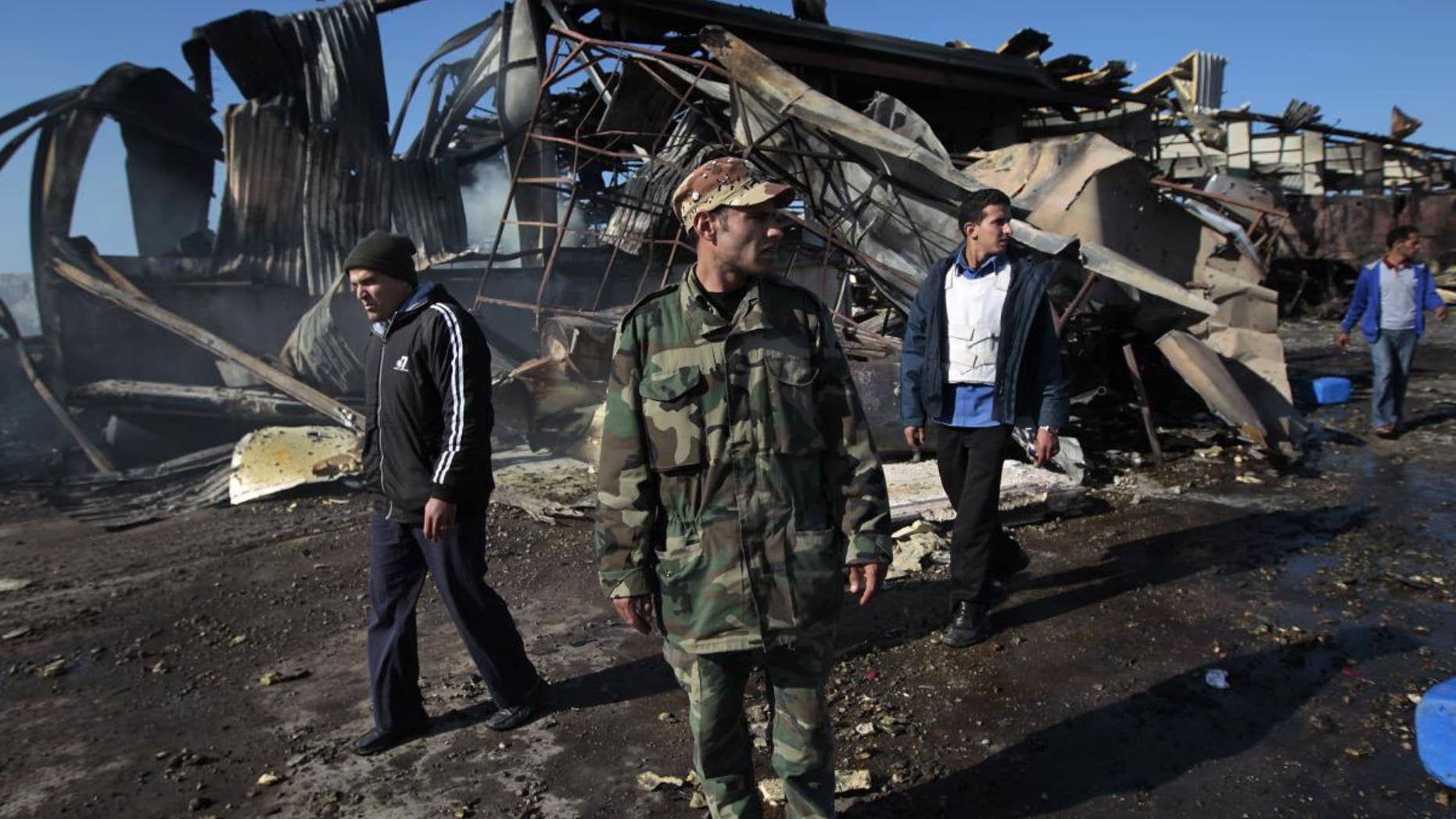 A Libyan soldier walks outside wreckage/AP Photo