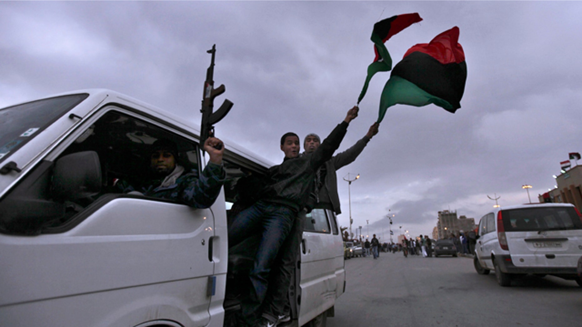 March 30: A Libyan rebel fires in air as others wave Libyan pre-Qaddafi flags as they ride a vehicle at twilight in Benghazi, Libya.