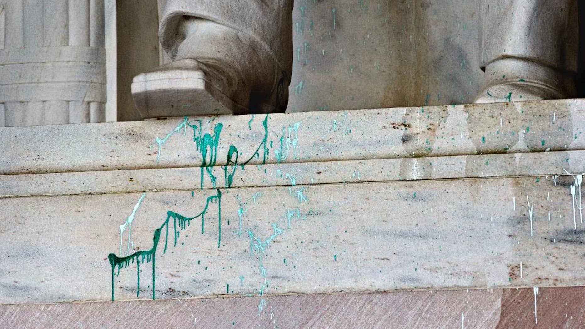 FILE - In this July 26, 2013 file photo, green paint splattered on the base of the statue of Abraham Lincoln at the Lincoln Memorial in Washington. A woman accused of splattering green paint at the Washington National Cathedral and suspected of committing similar vandalism at sites including the Lincoln Memorial in 2013 will not be prosecuted. Online court records show that a judge on Tuesday dismissed the case against Jiamei Tian, 60, who was arrested in July 2013 after being caught in the National Cathedral holding what appeared to be a soda can containing green paint. (AP Photo/J. Scott Applewhite, File)