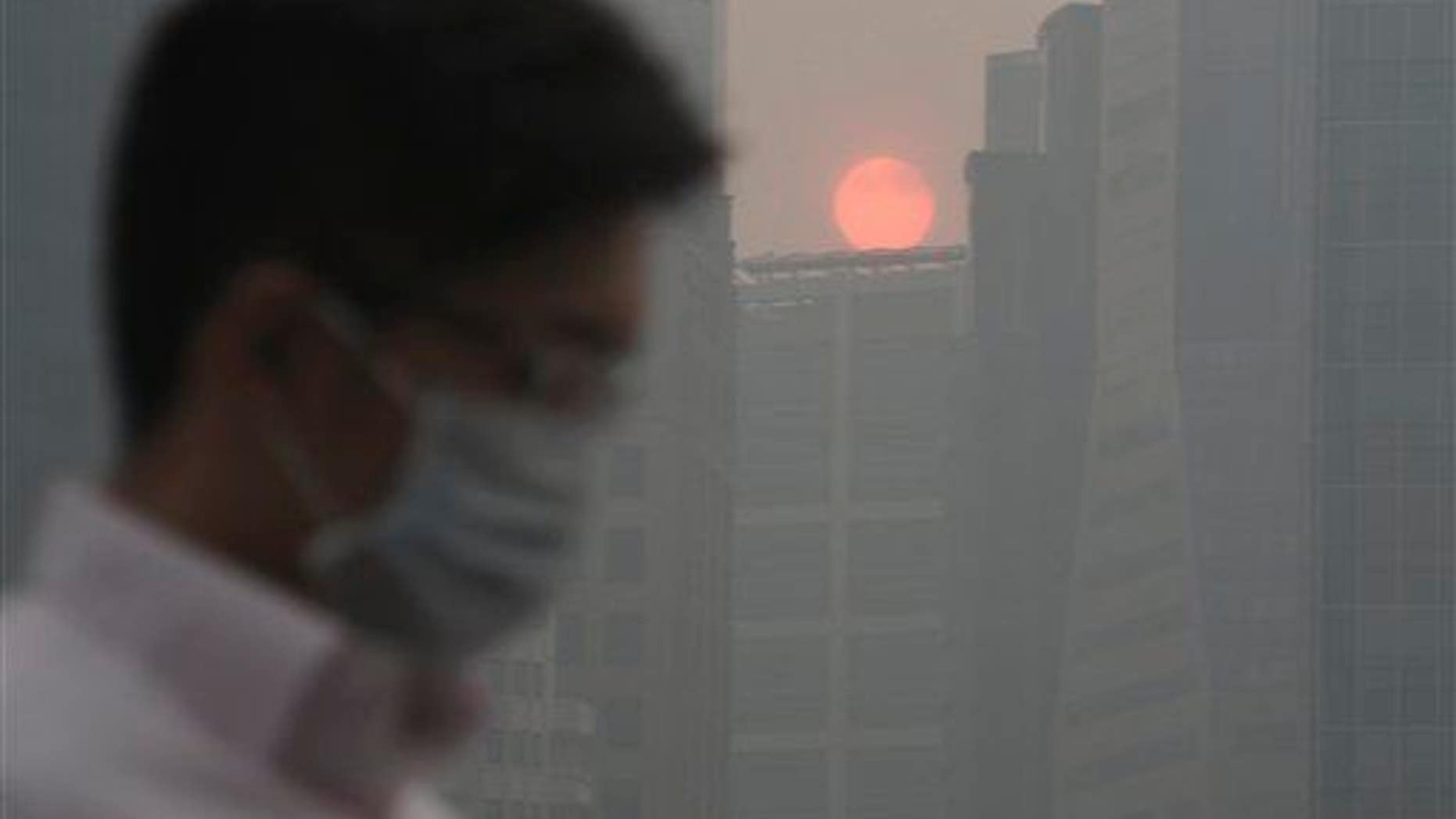 In this June 20, 2013 file photo, a masked man walks as the sun sets among buildings covered with haze, as Singapore urged people to remain indoors amid unprecedented levels of air pollution.