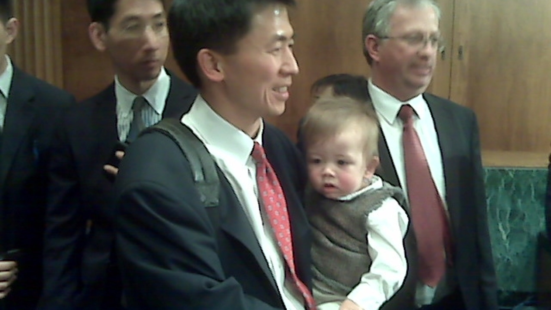 Goodwin Liu holds his son in the Senate Judiciary Committee room. (FNC Photo/Lee Ross)
