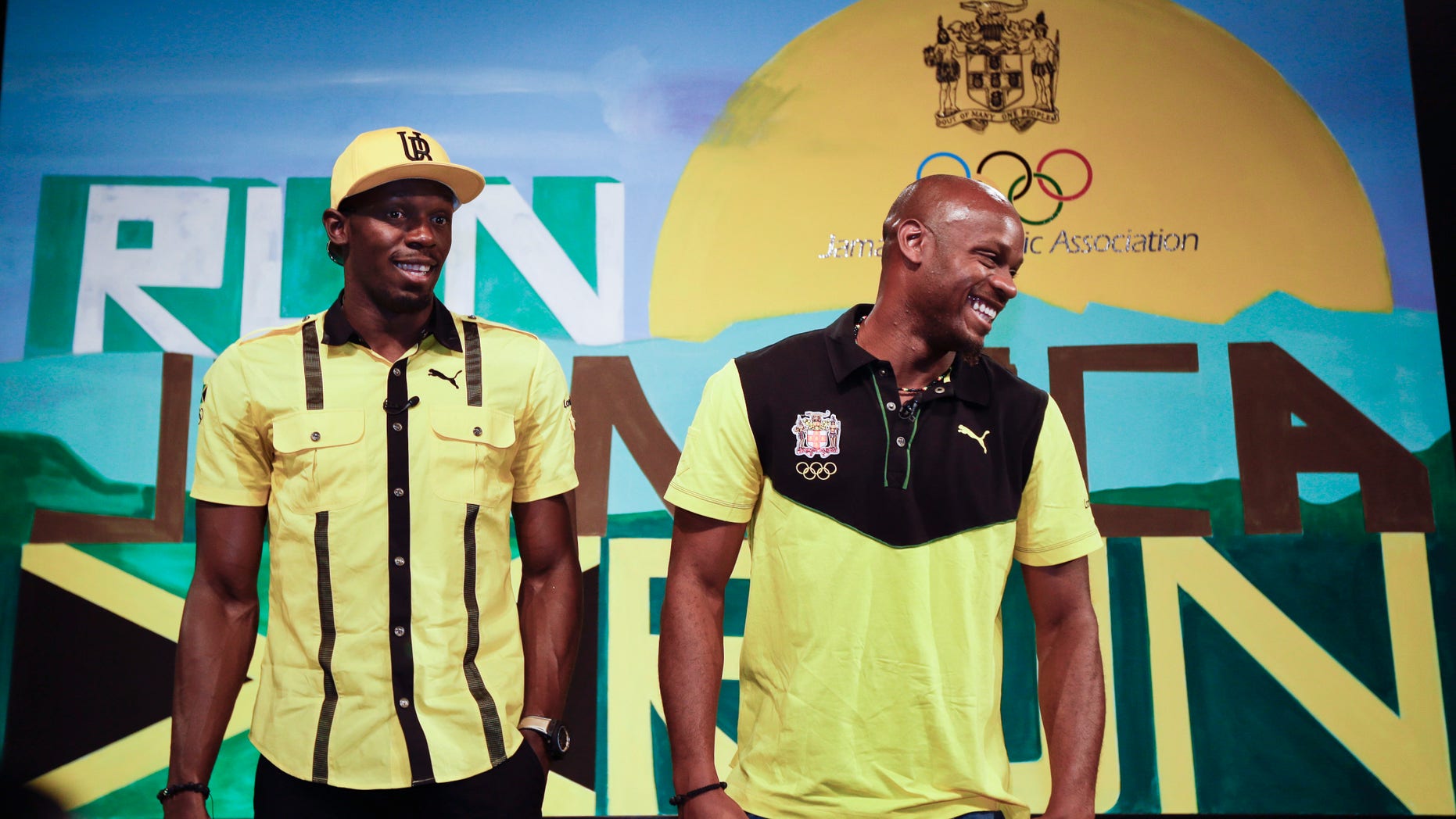 Jamaican sprinters Usain Bolt, left, and Asafa Powell, right, joke as they pose for photographers at the end of a press conference by the Jamaica Olympic Association ahead of the 2012 Summer Olympics, Thursday, July 26, 2012, in London. The opening ceremonies for the 2012 London Olympics will be held Friday, July 27. (AP Photo/Ben Curtis)