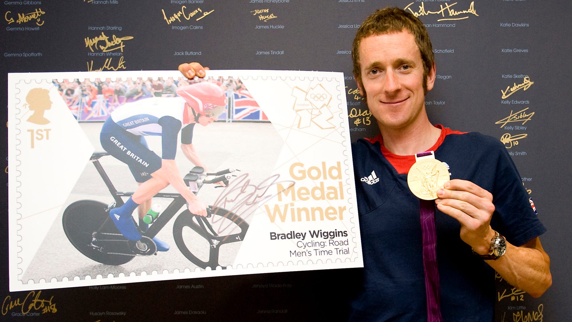 The handout photo provided by Royal Mail on Thursday, Aug. 2, 2012 shows British cyclist Bradley Wiggins with his gold medal and a new stamp celebrating his gold medal in the Men's Road Cycling Time Trial. (AP Photo/Royal Mail)