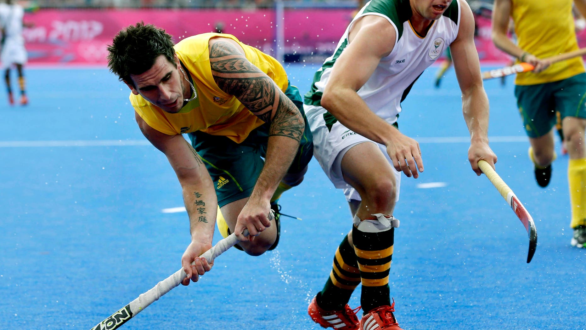 Australia's Kieran Govers, left, shoots towards the goal as South Africa's Andrew Cronje defends during a men's field hockey preliminary match at the 2012 Summer Olympics, Monday, July 30, 2012, in London. (AP Photo/Bullit Marquez)