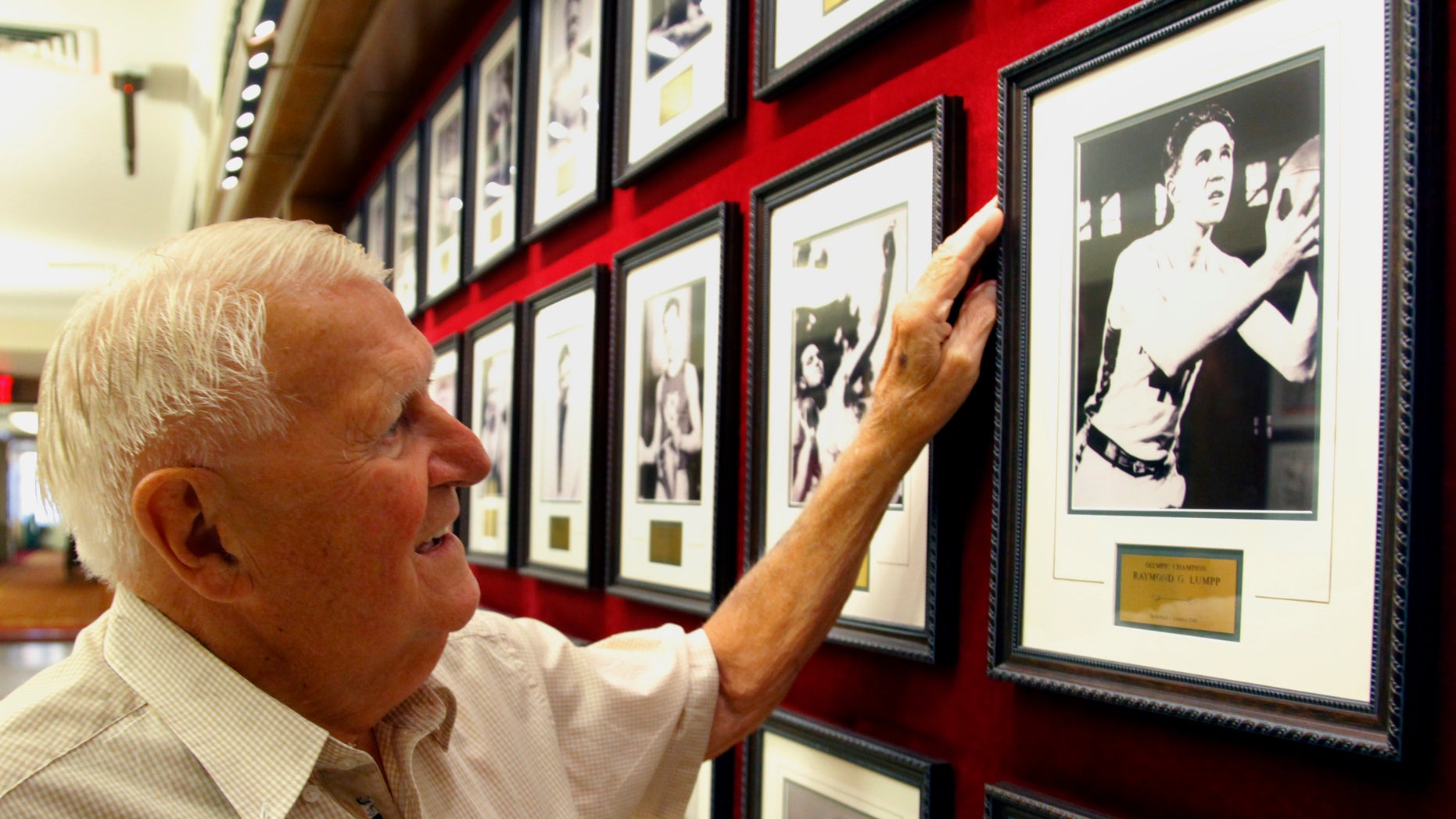 FILE - This Sept. 2, 2011 file photo shows Ray Lumpp, basketball gold medalist for the U.S. at the 1948 Olympics in London, pointing out his photo among those reserved for Olympic champions, at the New York Athletic Club. When the U.S. men's basketball team play Argentina on Friday night, the 89-year-old Lumpp promises to cheer louder than anyone else. (AP Photo/Bebeto Matthews, File)