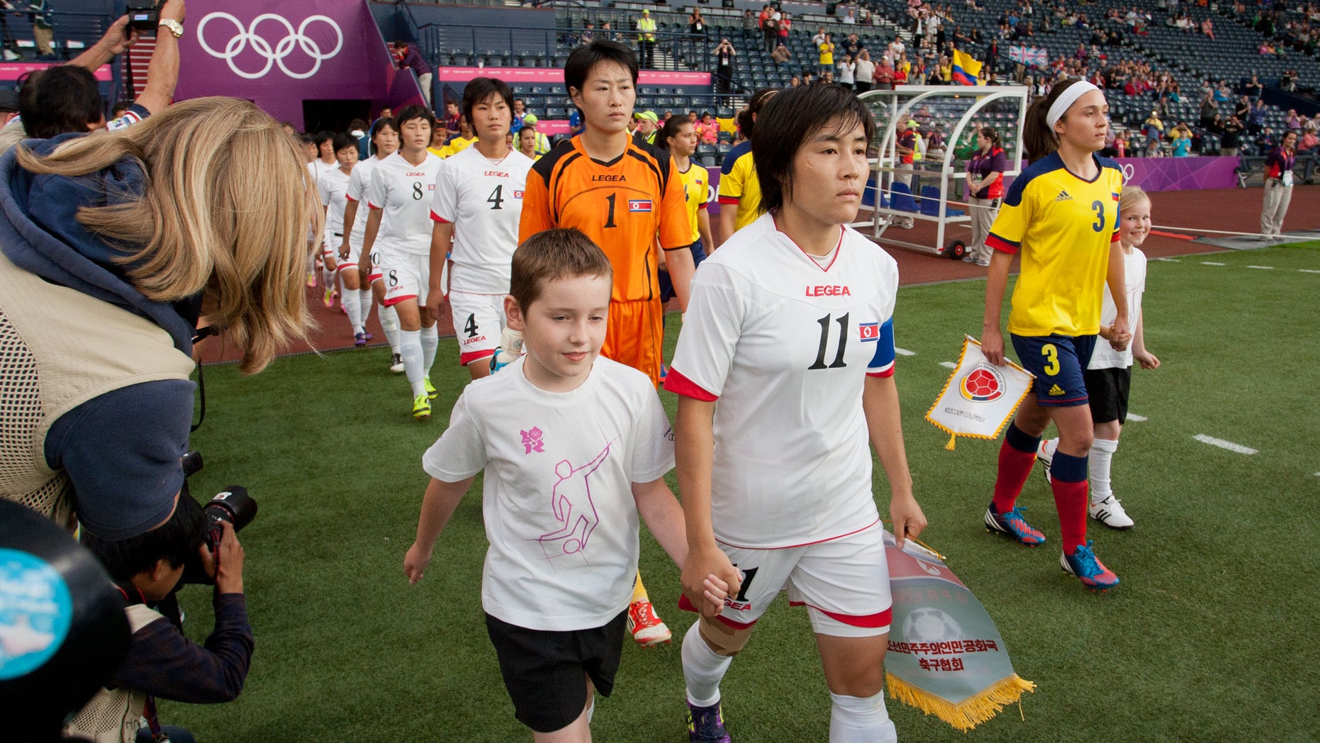 July 25, 2012: The North Korean, center, and Colombian women's soccer team walk out on to the field before their group B match, prior to the start of the London 2012 Summer Olympics at Hampden Park Stadium in Glasgow.