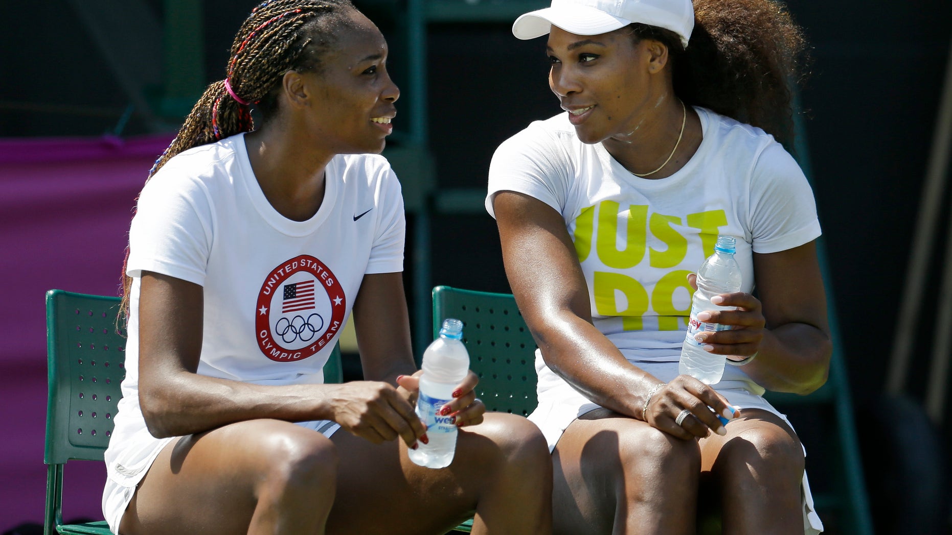 Venus, left, and Serena Williams, of the United States, talk during a break in practice at the All England Lawn Tennis Club at Wimbledon, in London, at the 2012 Summer Olympics, Thursday, July 26, 2012. Tennis competition is scheduled to begin Saturday, July 28. (AP Photo/Mark Humphrey)