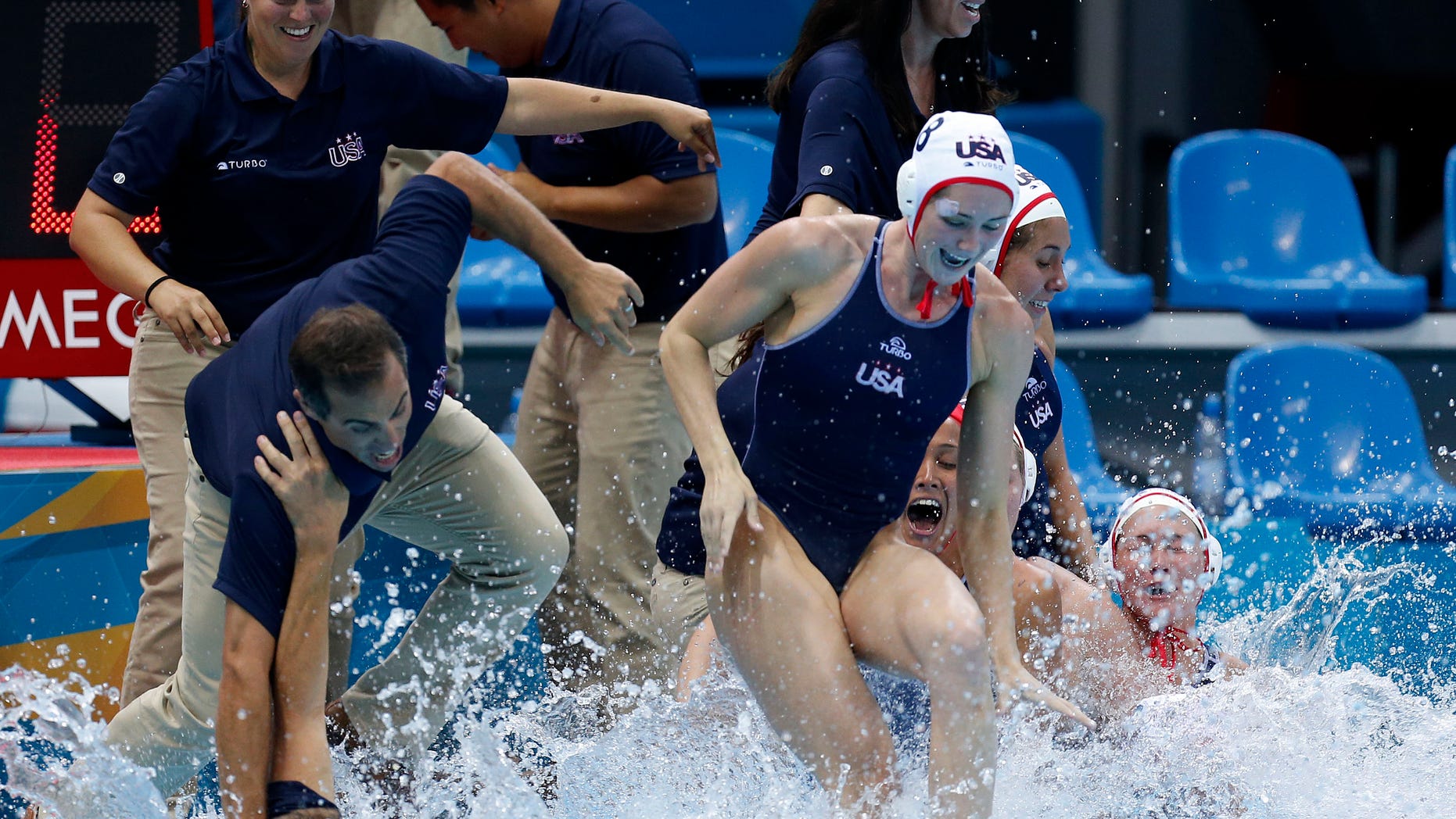 United States coach Adam Krikorian, left, is pulled into the pool moments after the team beat Spain during the gold medal women's water polo match at the 2012 Summer Olympics, Thursday, Aug. 9, 2012, in London. (AP Photo/Julio Cortez)