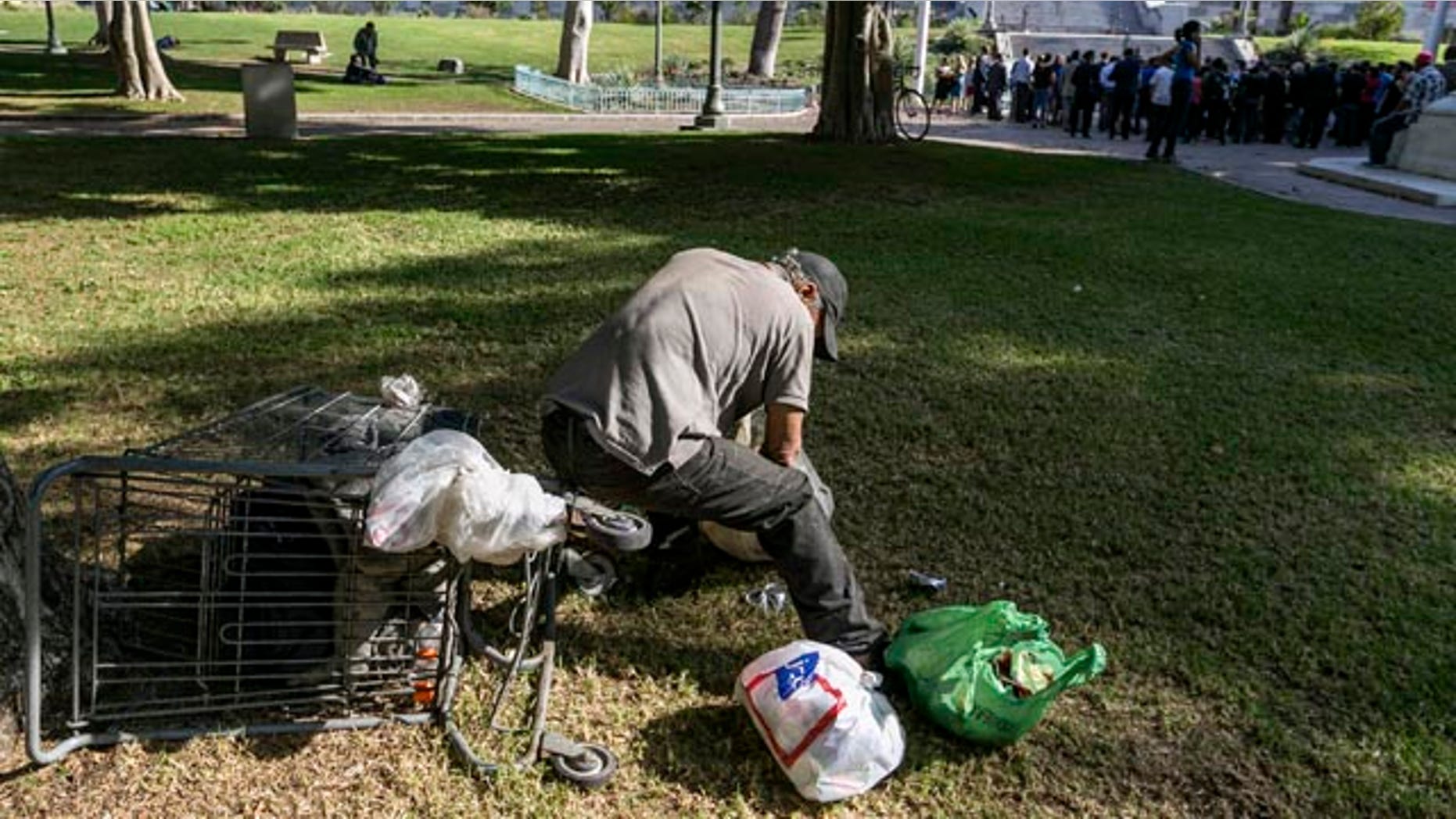 Sept. 22, 2015: A person sorts recyclable cans on the south lawn of City Hall in Los Angeles. Los Angeles officials gathered in the background said they will declare a state of emergency on homelessness and proposed spending $100 million to reduce the number of people living on city streets, as homeless people dozed nearby on a lawn and sidewalks. (AP Photo/Damian Dovarganes)