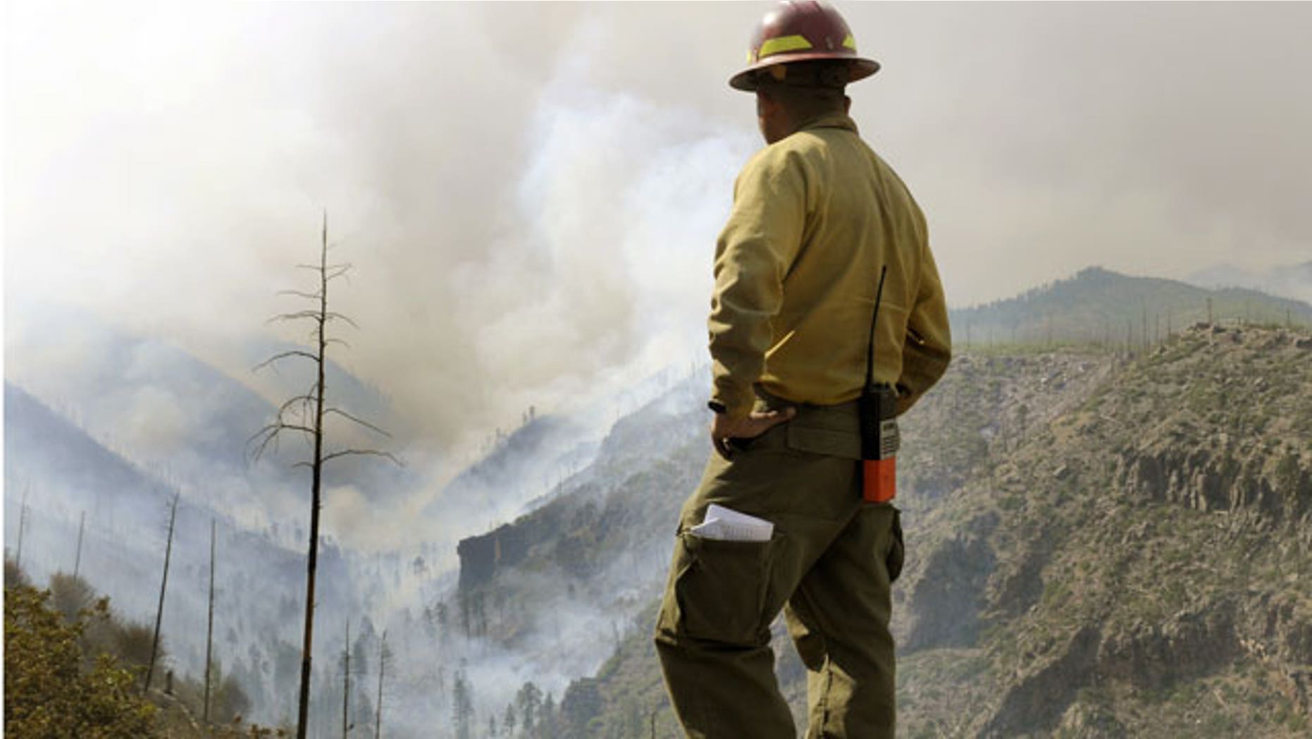 Firefighter Eugene Pino stands high above a smoke filled Los Alamos Canyon, Friday July 1, 2011 near Los Alamos, N.M.