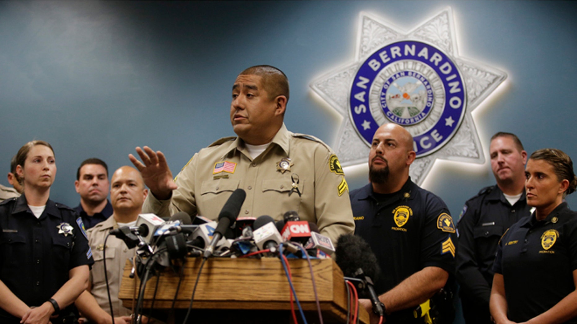 San Bernardino County Sheriff's detective Jorge Lozano, center, answers questions from reporters during a news conference with the first responders on the scene of last week's shooting, Tuesday, Dec. 8, 2015, in San Bernardino, Calif. Lozano was captured on video in a hallway of the Inland Regional Center telling employees and others who were stranded to follow him and that he would "take a bullet before you do." (AP Photo/Jae C. Hong)