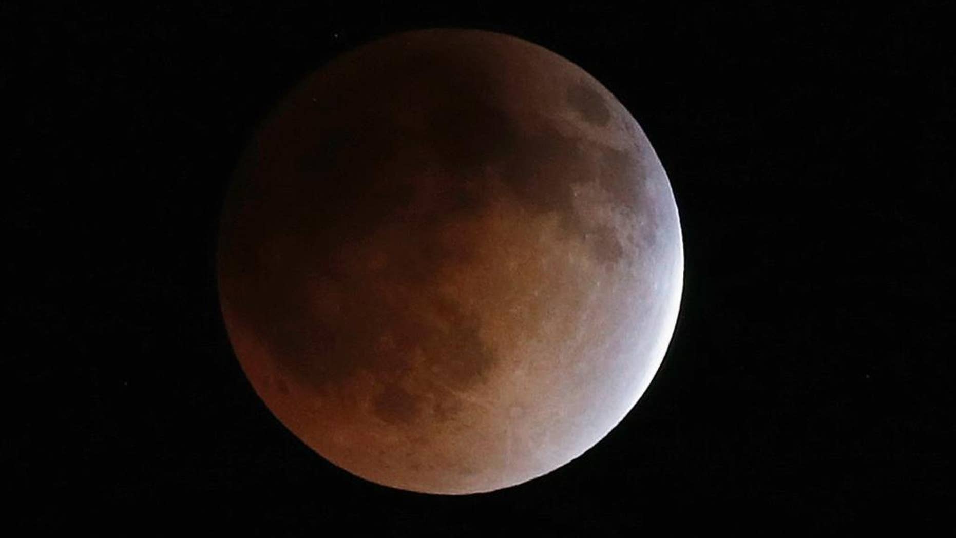 FILE - In this Tuesday, April 15, 2014, file photo, the moon turns an orange hue during a total lunar eclipse in the sky above Phoenix. On Wednesday morning, Oct. 8, 2014, North Americans will have prime viewing of a full lunar eclipse, especially in the West. The total eclipse will last an hour, until sunrise on the East Coast. (AP Photo/Ross D. Franklin, File)