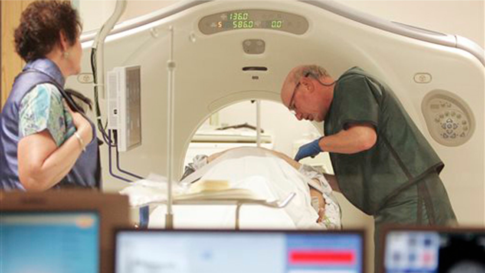 FILE - In this June 3, 2010, file photo, Dr. Steven Birnbaum works with a patient in a CT scanner at Southern New Hampshire Medical Center in Nashua, N.H. A national study suggests the world's top cancer killer isn't always as deadly as doctors once thought, finding that more than 18 percent of lung cancers detected in screening scans are likely so slow growing that theyâd never cause problems. But the provocative results are unlikely to change how doctors treat lung cancer. (AP Photo/Jim Cole, File)