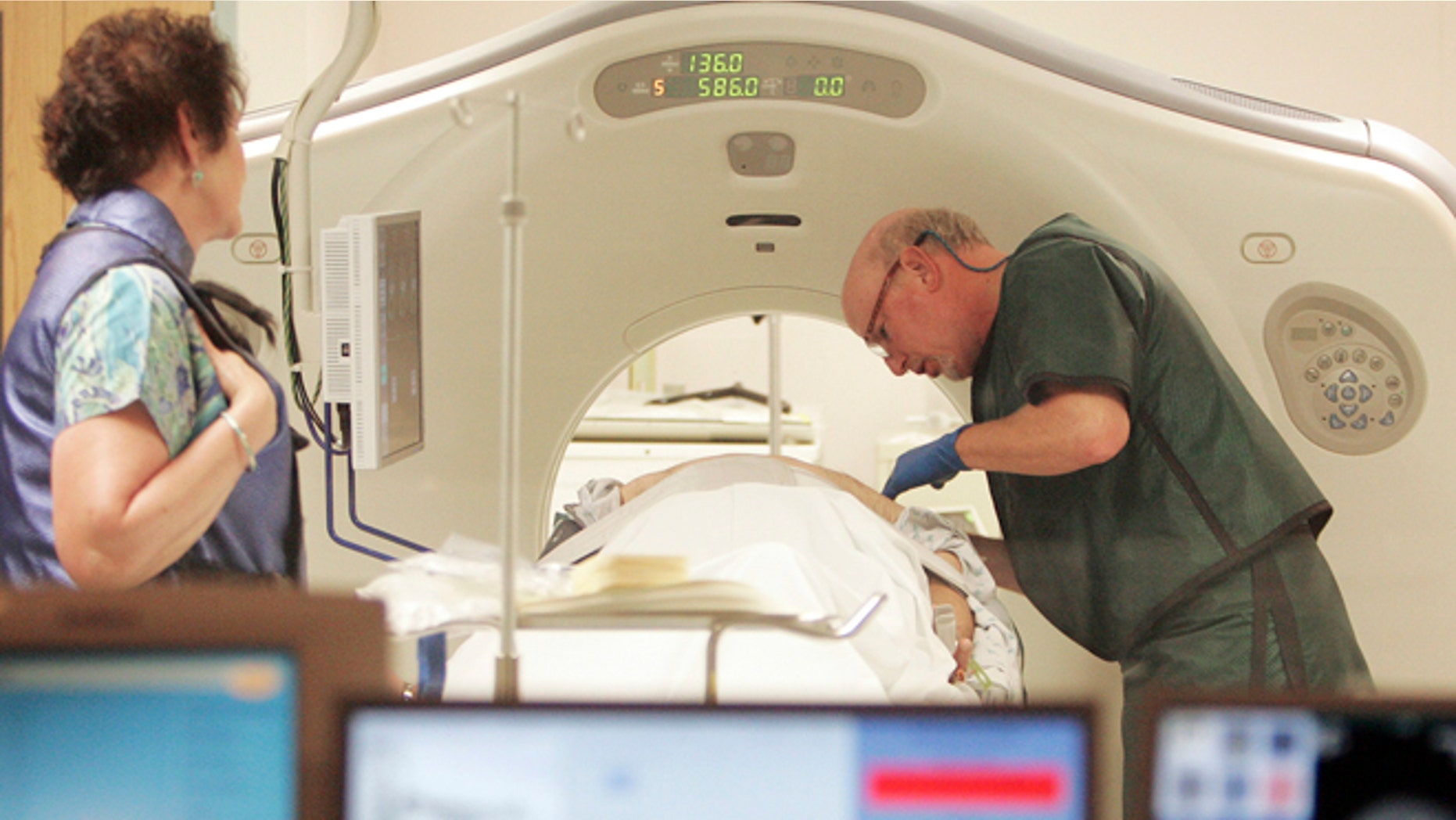 FILE - In this June 3, 2010, file photo, Dr. Steven Birnbaum works with a patient in a CT scanner at Southern New Hampshire Medical Center in Nashua, N.H. A national study suggests the world's top cancer killer isn't always as deadly as doctors once thought, finding that more than 18 percent of lung cancers detected in screening scans are likely so slow growing that theyâd never cause problems. But the provocative results are unlikely to change how doctors treat lung cancer. (AP Photo/Jim Cole, File)