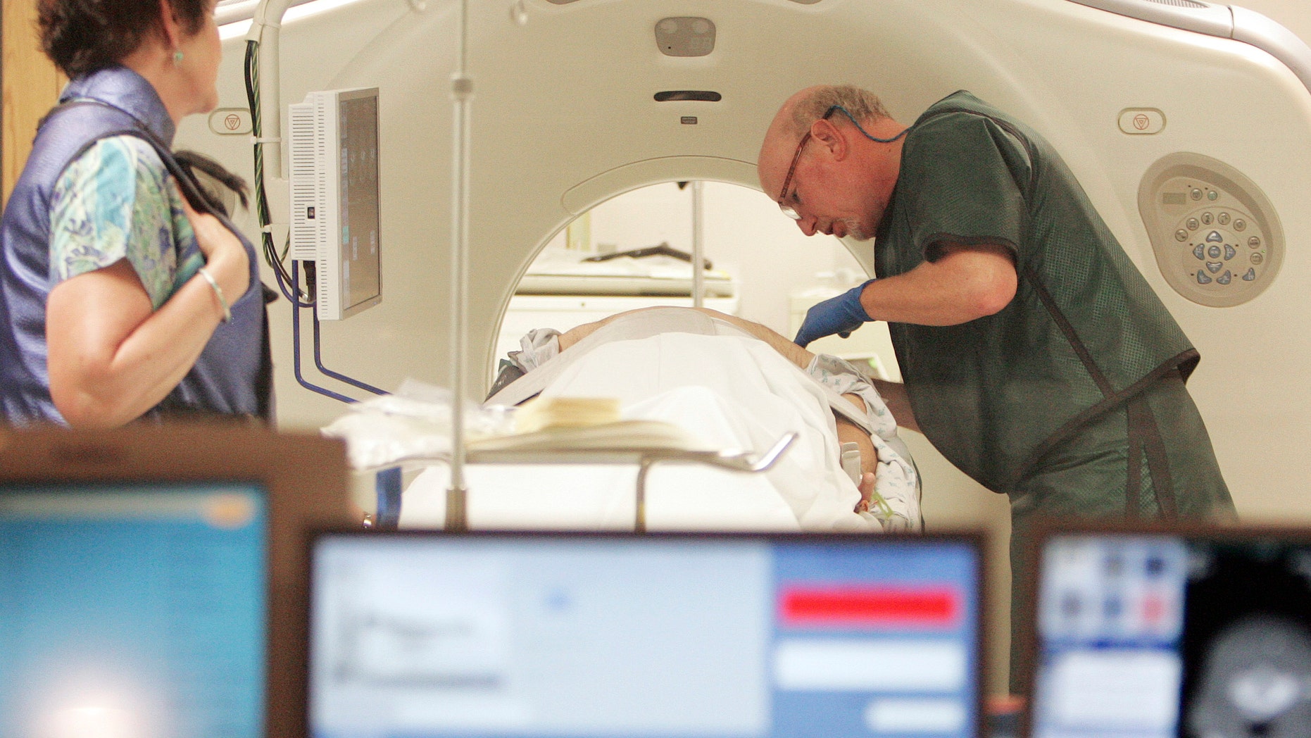 Dr. Steven Birnbaum works with a patient in a CT scanner at Southern New Hampshire Medical Center in Nashua, N.H. A new study estimates that screening certain current and former smokers for lung cancer would cost Medicare about $2 billion a year, which would add $3 a month to Medicare premiums. (AP Photo/Jim Cole, File)