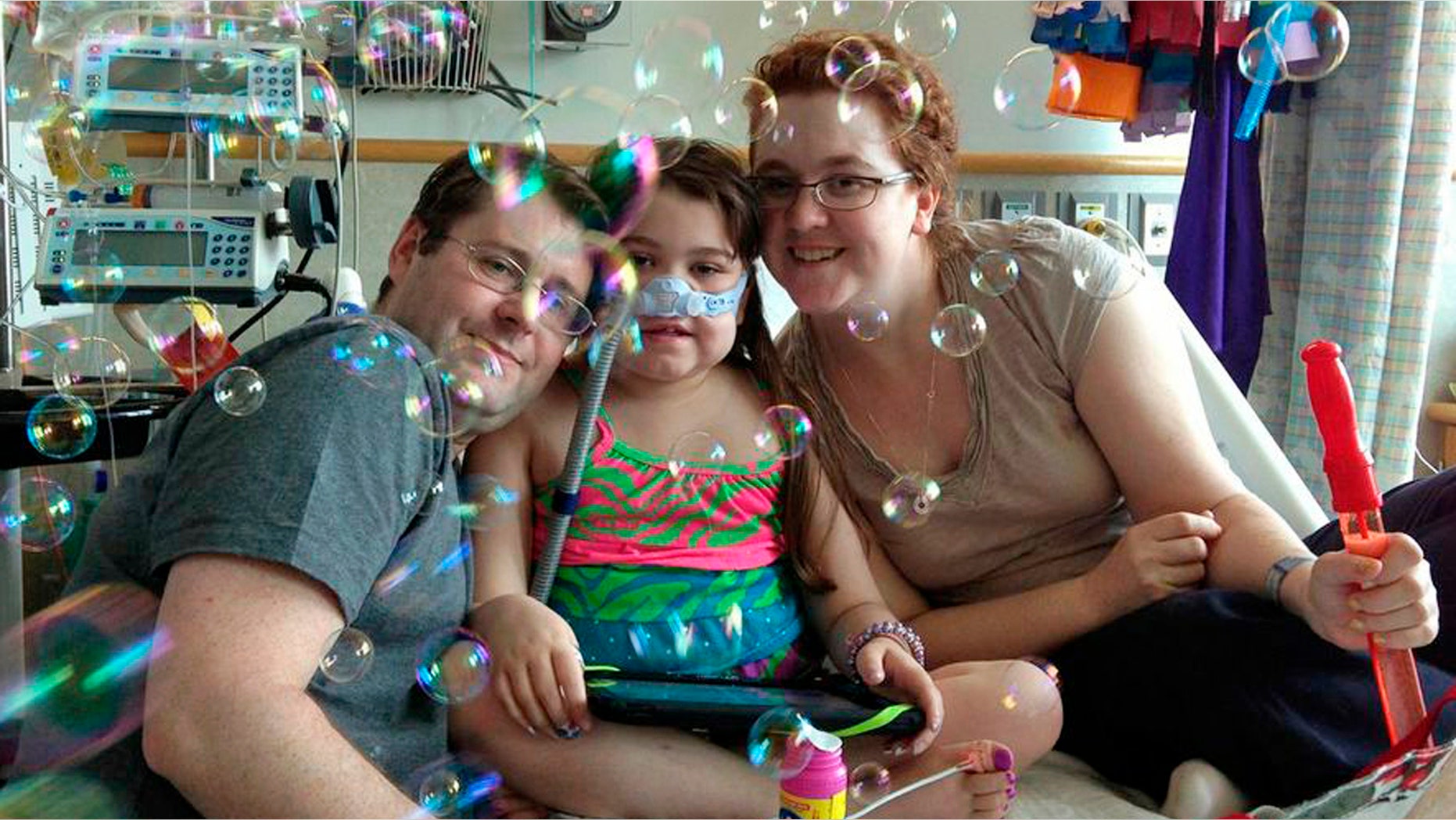 FILE - In this May 30, 2013 file photo provided by the Murnaghan family, Sarah Murnaghan, center, celebrates the 100th day of her stay in Children's Hospital of Philadelphia with her father, Fran, left, and mother, Janet. The 10-year-old suburban Philadelphia girl received a lung transplant there Wednesday, June 12, 2013, her family said. (AP Photo/Murnaghan Family, File)