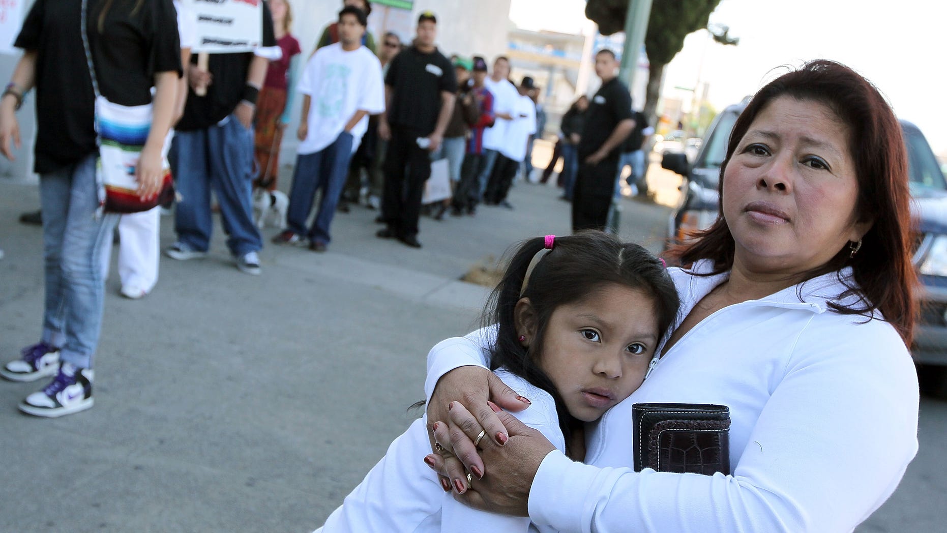 OAKLAND, CA - APRIL 30: A woman embraces her child as they watch the group "Youth United For Justice" protest Arizona's new immigration law April 30, 2010 in Oakland, California. Dozens of people marched in protest of Arizona state bill 1070 which was signed into law this past week and gives law enforcement officials unprecedented authority to stop and question suspected illegal immigrants. (Photo by Justin Sullivan/Getty Images)