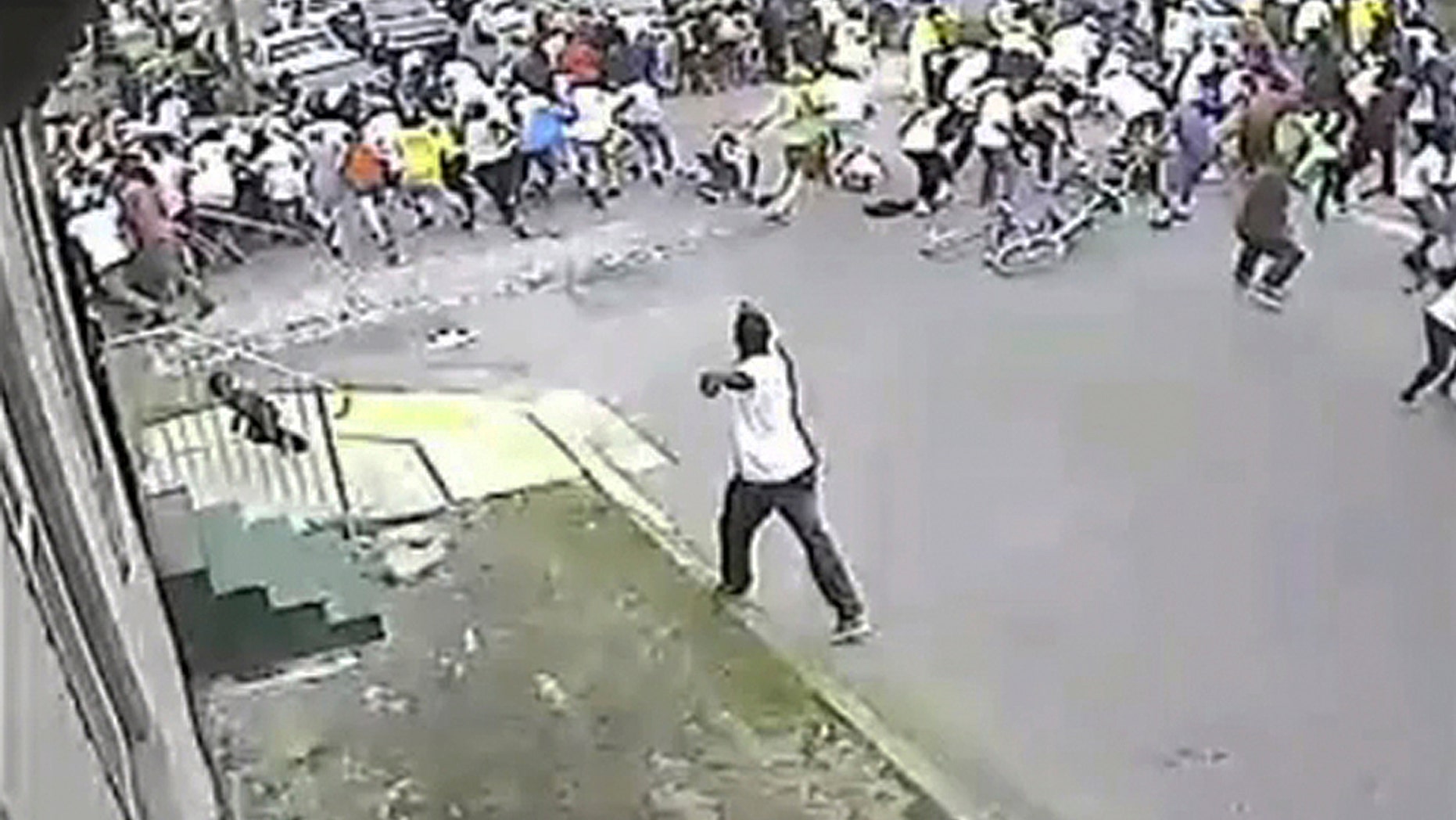 May 12, 2013: A man in a white shirt, bottom center, shoots into a crowd of people, on Mother's Day in New Orleans. New Orleans officials and cultural advocates say the Mothers Day parade shootings that left 20 people injured won't spell the end of second-line parades.