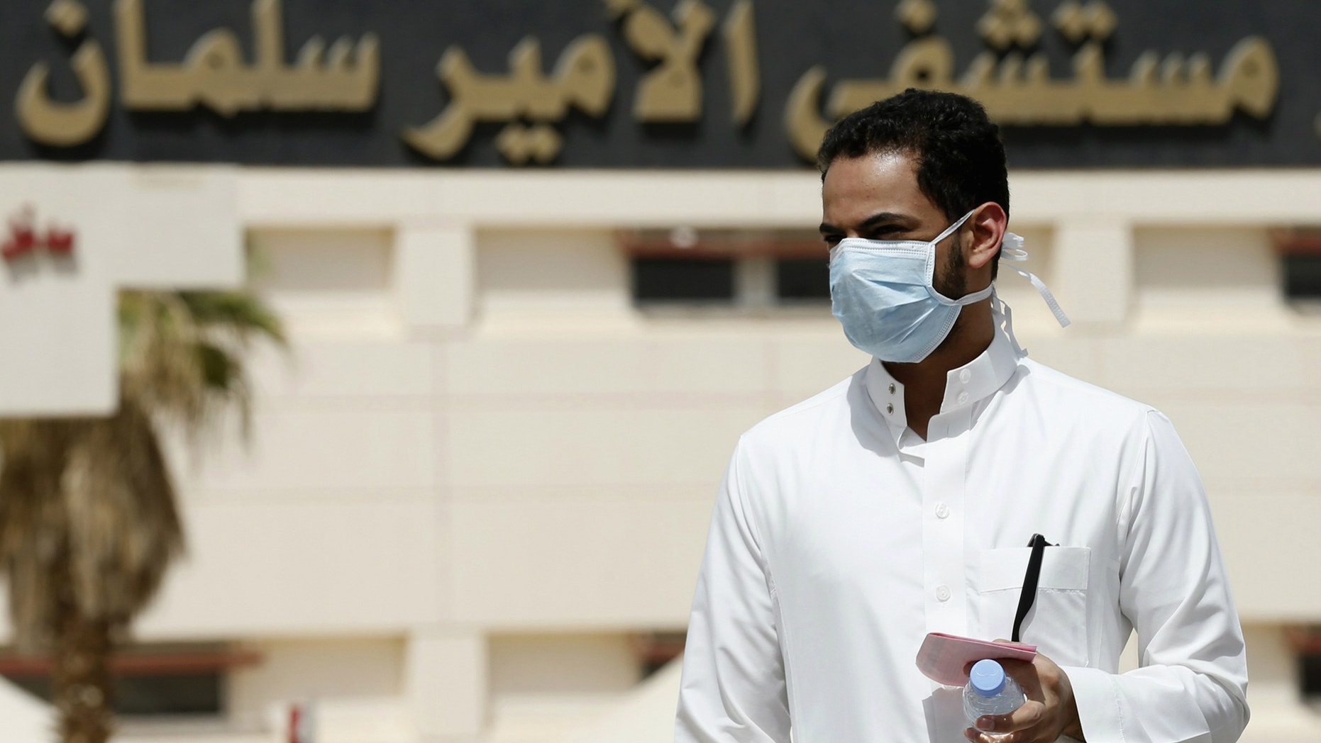 A man wearing a mask walks outside Prince Salman bin Abdulaziz hospital, in Riyadh.
