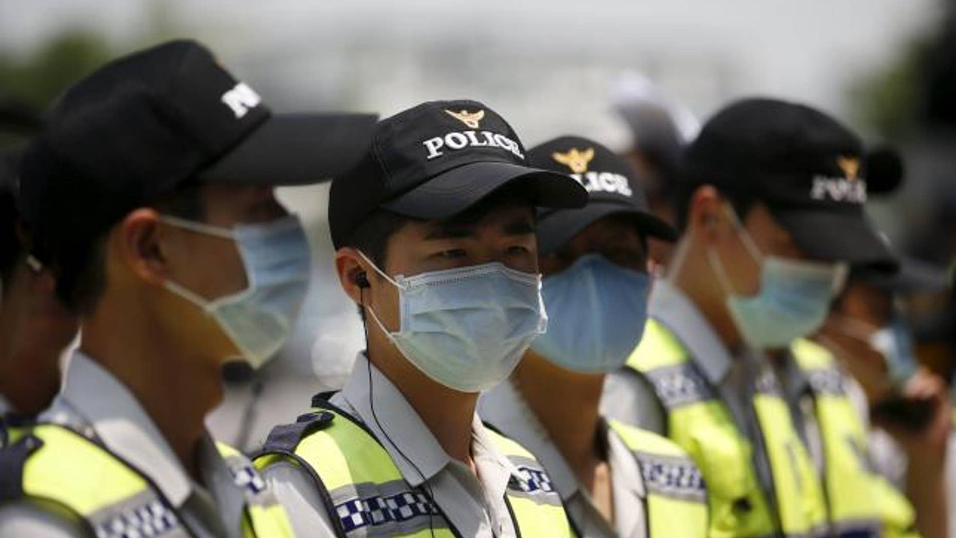 June 22, 2015: Policemen wearing masks to prevent contracting Middle East Respiratory Syndrome (MERS) stand guard in front of Japanese Embassy in Seoul, South Korea.