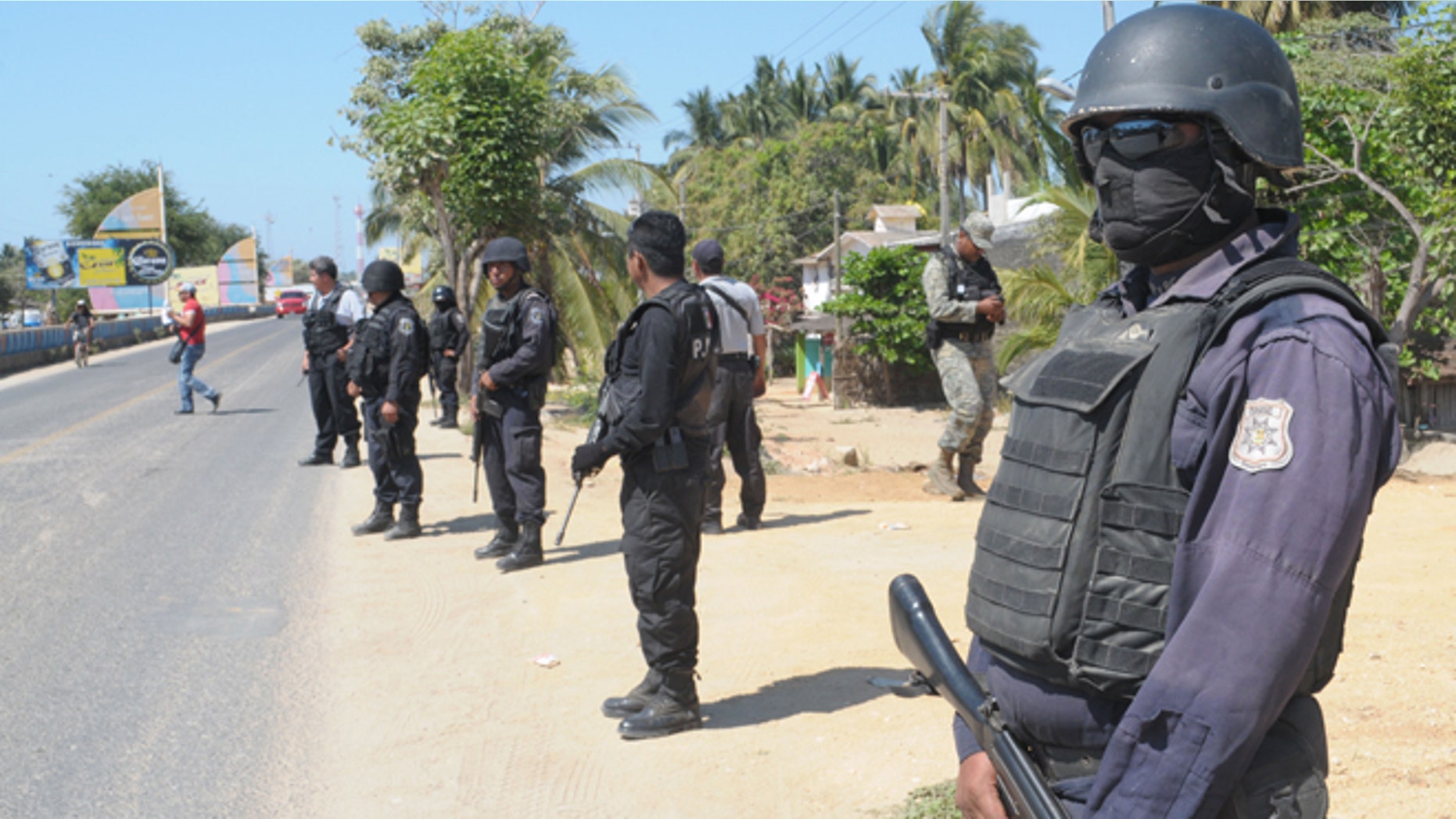 State police stand at a roadblock due to stepped up security after masked armed men broke into a beach home, raping six Spanish tourists who had rented the house in Acapulco, Mexico, Tuesday Feb. 5, 2013.