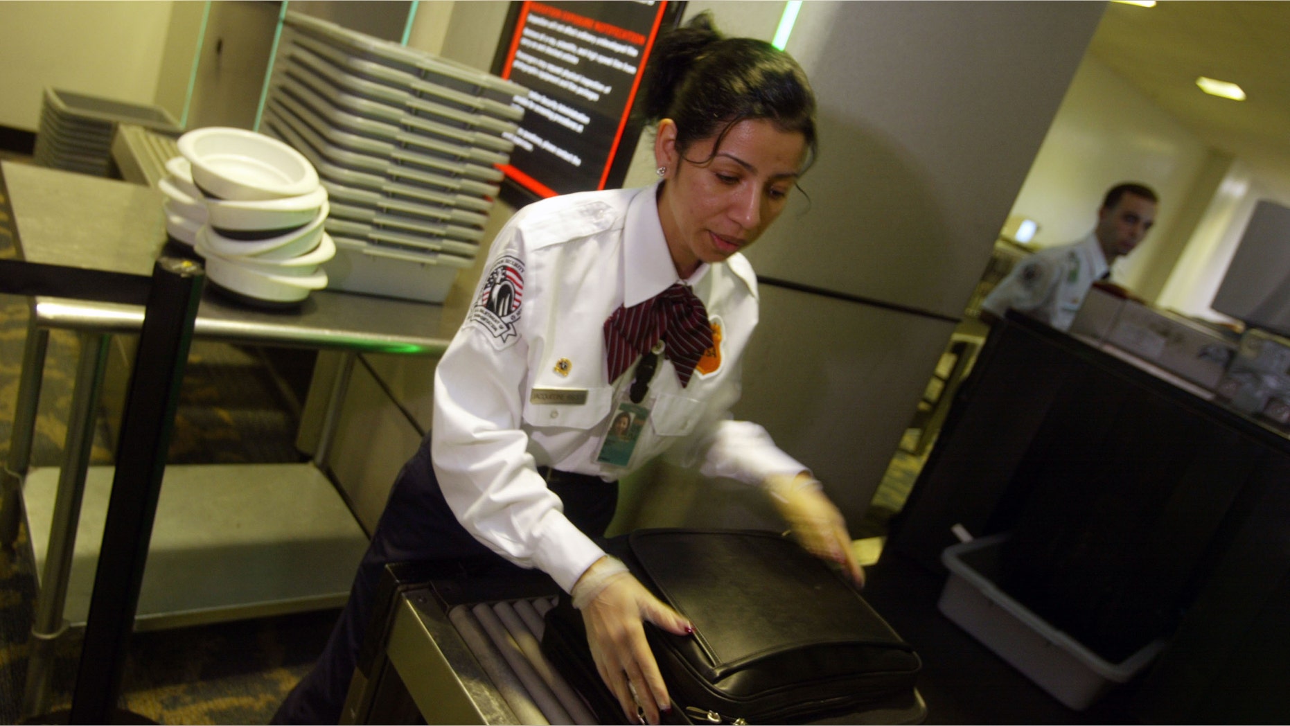 MIAMI - SEPTEMBER 30: Transportation Security Administration screener Jackie Neal puts a briefcase through the scanner at the Miami International Airport September 30, 2003 in Miami. The deadline for the agency to trim airport screeners nationwide by another 3,000 positions is September 30. (Photo by Joe Raedle/Getty Images)