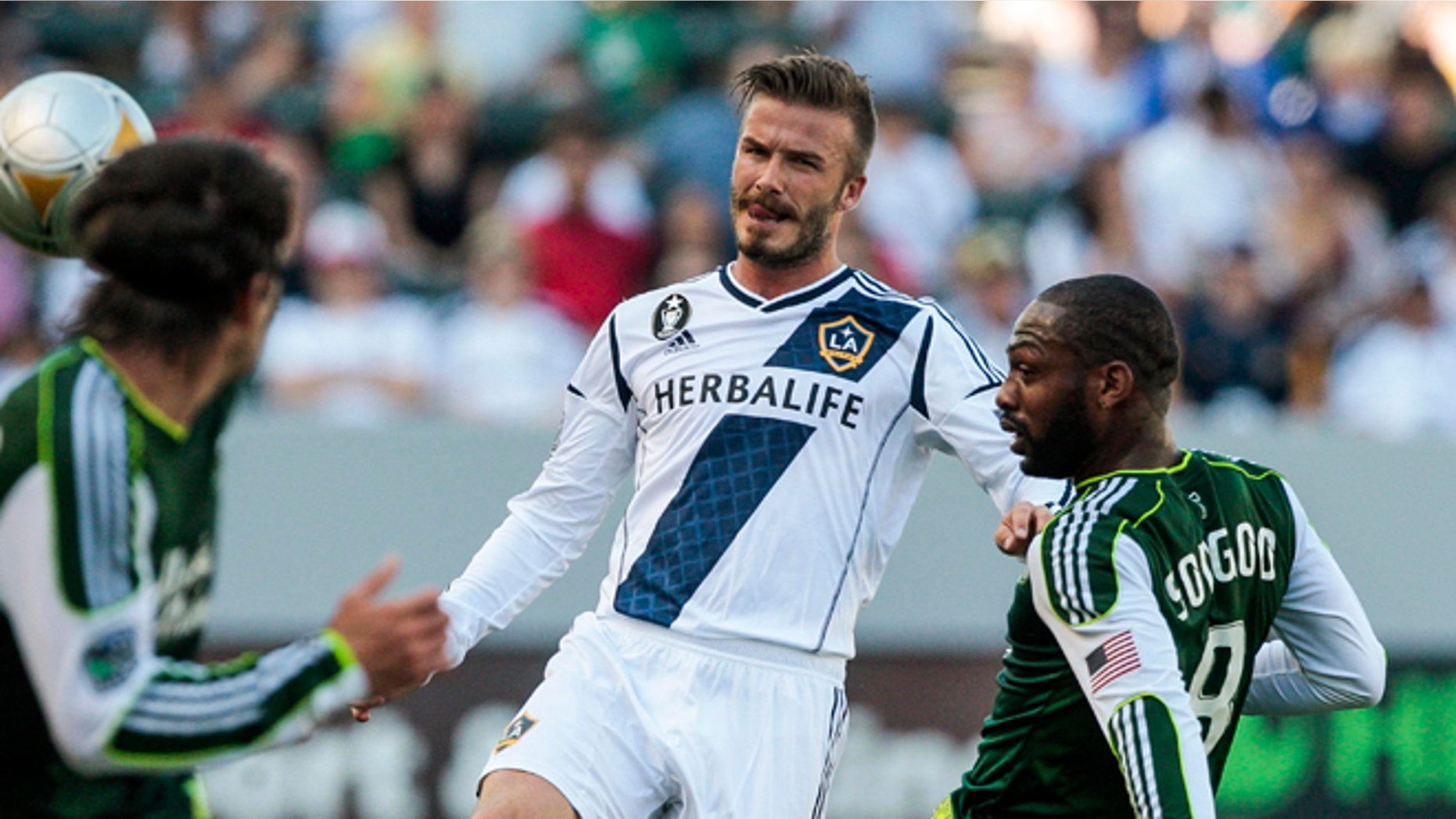 June 17, 2012: Los Angeles Galaxy midfielder David Beckham, center, makes a pass around Portland Timbers midfielder Franck Songo'o, right, as Portland Timbers defender Mike Chabala, left, gives chase during the first half of an MLS soccer match in Carson, Calif.