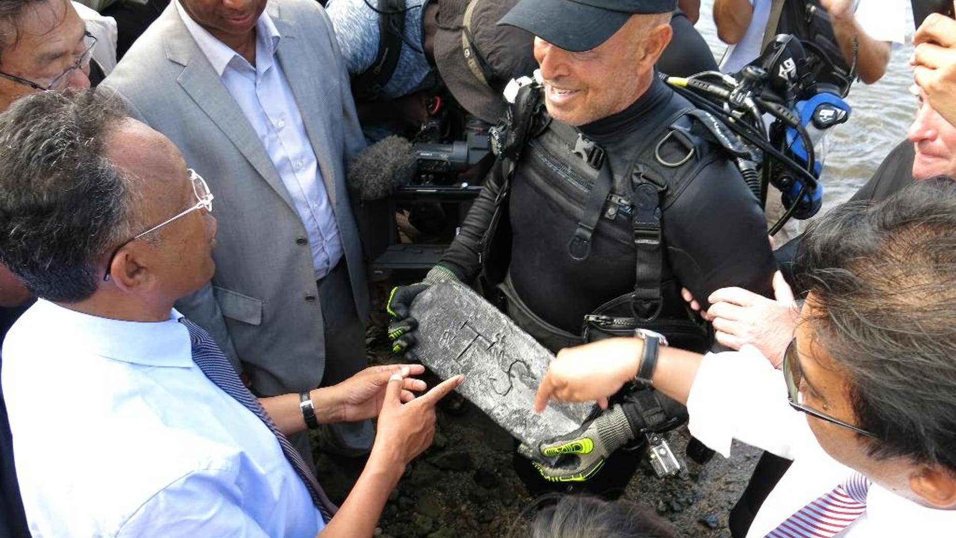 In this photo taken Thursday, May, 7, 2015 underwater explorer Barry Clifford, right, presents a silver bar he believes is part of the treasure of the pirate Captain Kidd, to the president of Madagascar, Hery Rajaonarimampianina, left, on Sainte Marie Island, Madagascar. (AP Photo/Martin Vogl)