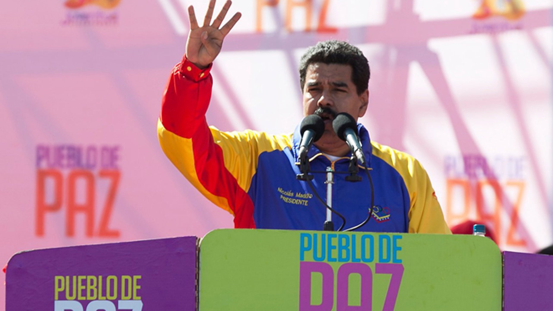 Venezuela's President Nicolas Maduro speaks during a rally on Bolivar Avenue in downtown Caracas, Venezuela, Saturday, Feb. 15, 2014. The signs read in Spanish "People of peace." Maduro said a police manhunt is underway for opposition leader Leopoldo Lopez, and denounced what he said is a "fascist" plot to oust him from power. (AP Photo/Alejandro Cegarra)