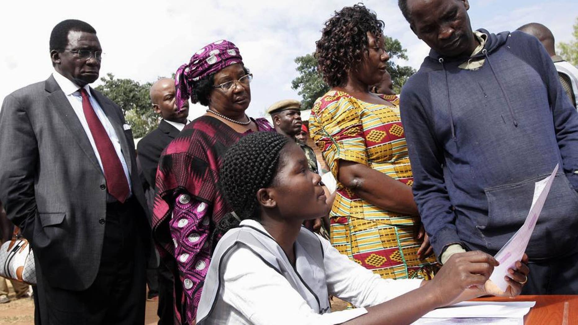 Background from left to right, Chief Justice Richard Banda, his wife, Malawi President Joyce Banda, and younger sister Anjimile Mtila-Oponyo, join a voting queue to cast their votes in the eastern district of Zomba, Malawi, Tuesday, May 20, 2014. Africa's second female president Joyce Banda is facing stiff challenges from a field of 12 candidates in Malawi's elections Tuesday. (AP Photo/Raphael Tenthani)