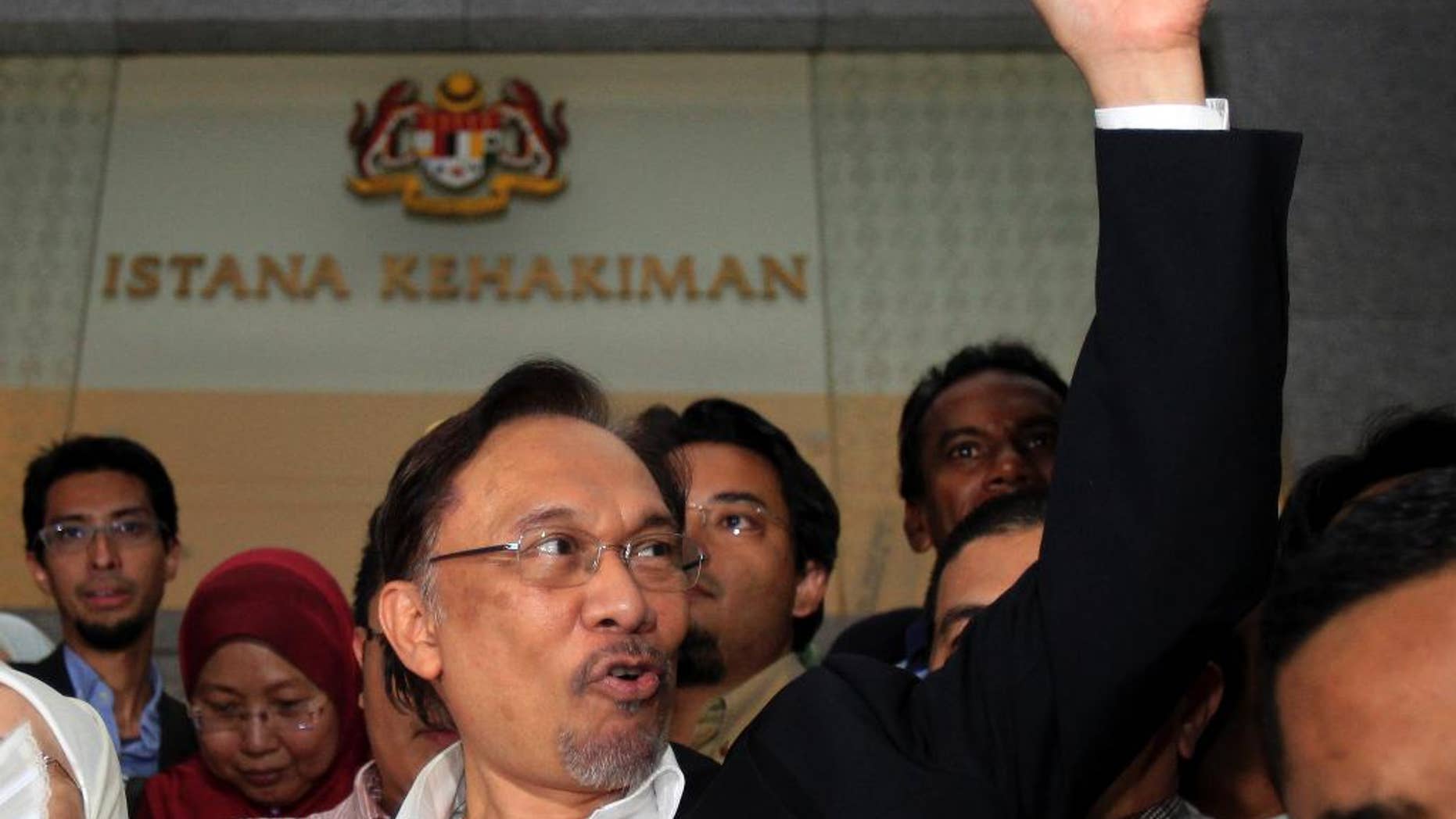 FILE - In this Friday, March 7, 2014 file photo, Malaysian opposition leader Anwar Ibrahim gestures as he leaves a courthouse in Putrajaya, Malaysia. Anwar said late Tuesday, Oct. 21, 2014 he expects Malaysia’s top court will dismiss his final appeal against a sodomy conviction next week and that he will be sent to prison. Anwar was sentenced to five years in prison in March on charges of sodomizing a male aide after the appeals court overturned an earlier acquittal. The Federal Court will hear his appeal Oct. 28-29. (AP Photo/Lai Seng Sin, File)