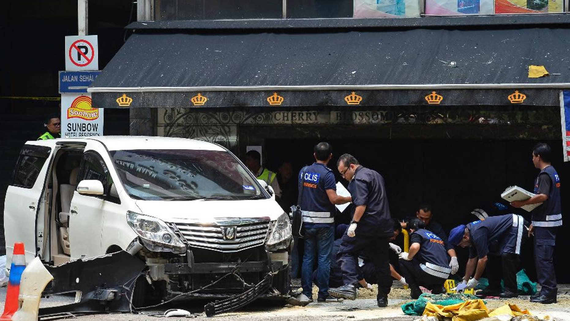 Malaysian forensic police officers investigate the scene where a grenade exploded outside a night club in Kuala Lumpur, Malaysia, Thursday, Oct. 9, 2014. Malaysian police say one person died and 13 others injured when a hand grenade blew up Thursday at the popular tourist belt in the country's largest city. (AP Photo) MALAYSIA OUT
