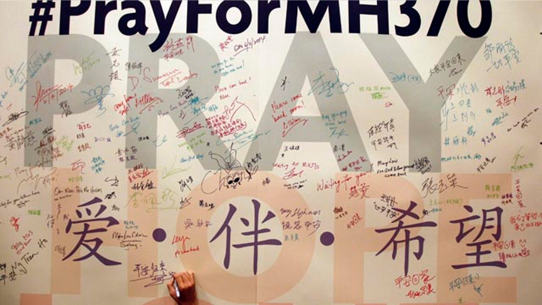 FILE - In this April 6, 2014 file photo, a man writes messages for passengers aboard the missing Malaysia Airlines Flight MH370 before a mass prayer for them, in Kuala Lumpur, Malaysia. (AP Photo/Lai Seng Sin, File)