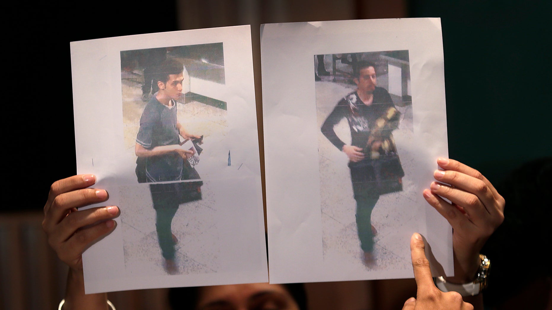 Pictures of the two men, a 19-year old Iranian, identified by Malaysian police as Pouria Nour Mohammad Mehrdad, left, and the man on the right, his identity still not released, who boarded the now missing Malaysia Airlines jet MH370 with stolen passports, is held up by a Malaysian policewoman during a press conference, Tuesday, March 11, 2014 in Sepang, Malaysia. One of the two men traveling on a missing Malaysian Airlines jetliner was an Iranian asylum seeker, officials said Tuesday, as baffled authorities expanded their search for the Boeing 777 on the opposite side of the country from where it disappeared nearly four days ago with 239 people on board.(AP Photo/Wong Maye-E)