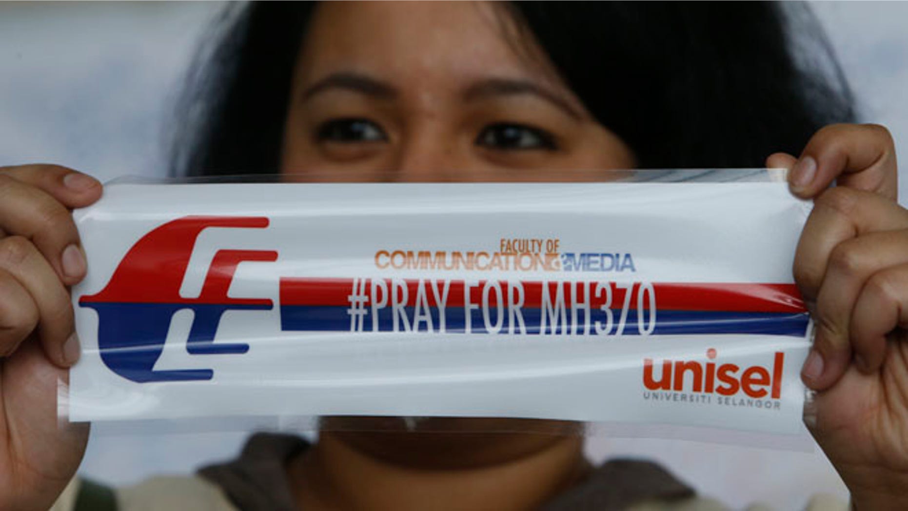 March 16, 2014.: A woman with a sticker on the passengers of the missing Malaysia flight, at Kuala Lumpur International Airport, Malaysia.