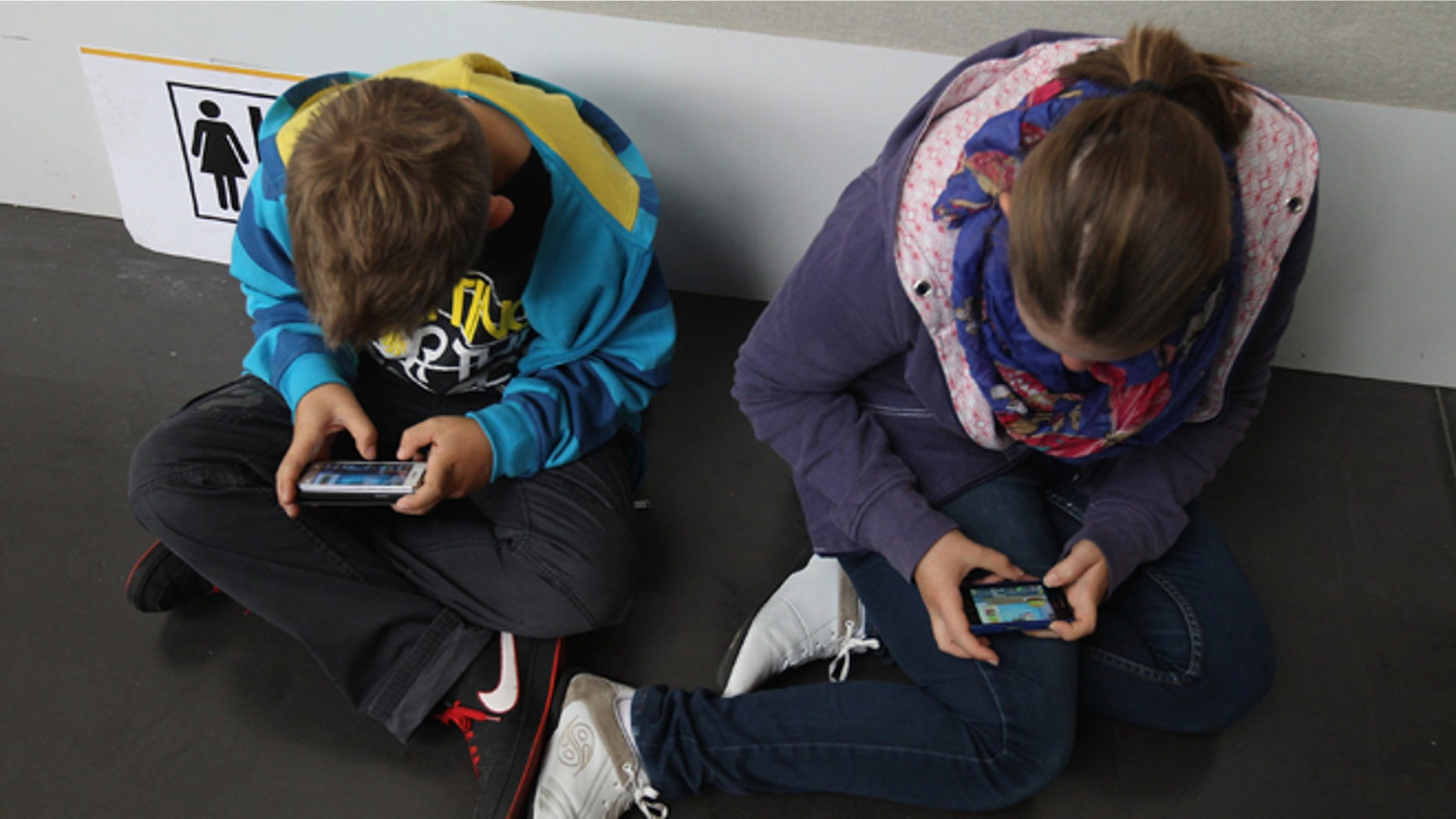 RUESSELSHEIM, GERMANY - SEPTEMBER 22: Children play video games on smartphones while attending a public event on September 22, 2012 in Ruesselsheim, Germany. Smartphones, with their access to social networks, high-resolution screens, video games and internet acess, have become commonplace among children and teenagers across the globe. (Photo by Sean Gallup/Getty Images)
