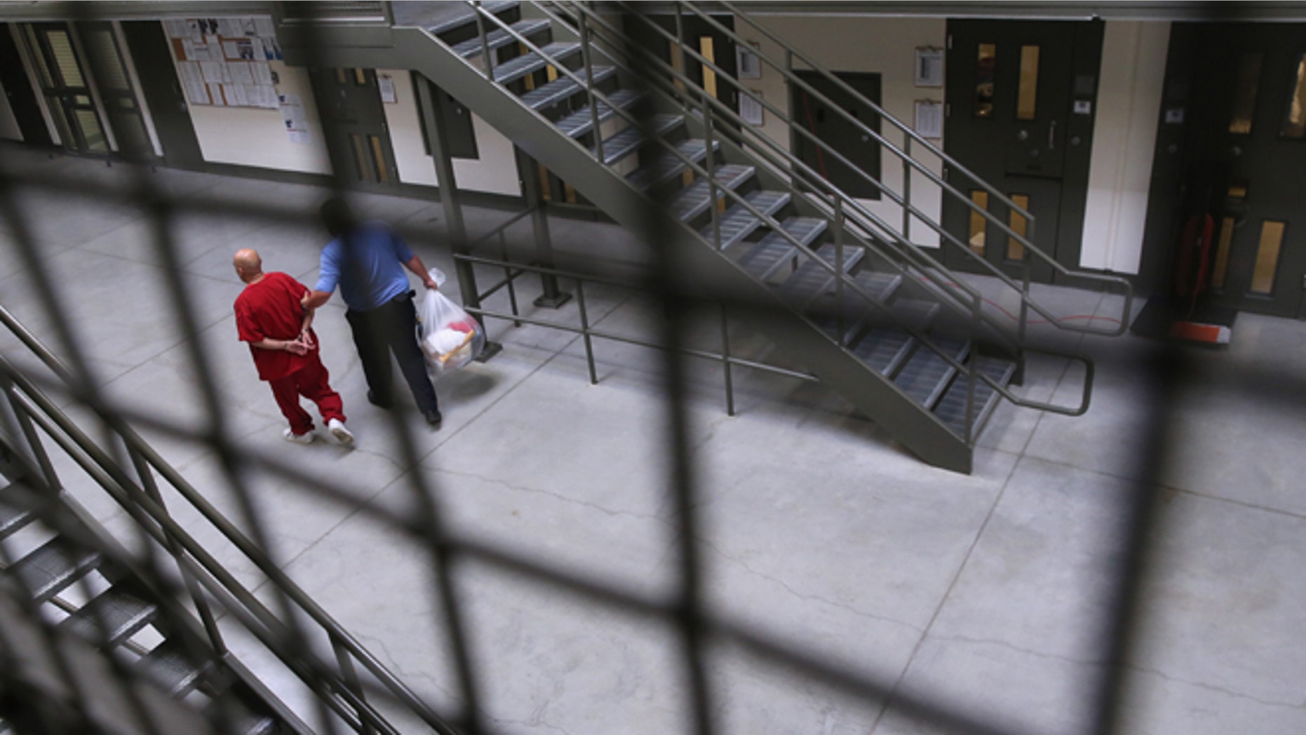 ADELANTO, CA - NOVEMBER 15: A guard escorts an immigrant detainee from his 'segregation cell' back into the general population at the Adelanto Detention Facility on November 15, 2013 in Adelanto, California. Most detainees in segregation cells are sent there for fighting with other immigrants, according to guards. The facility, the largest and newest Immigration and Customs Enforcement (ICE), detention center in California, houses an average of 1,100 immigrants in custody pending a decision in their immigration cases or awaiting deportation. The average stay for a detainee is 29 days. The facility is managed by the private GEO Group. ICE detains an average of 33,000 undocumented immigrants in more than 400 facilities nationwide. (Photo by John Moore/Getty Images)