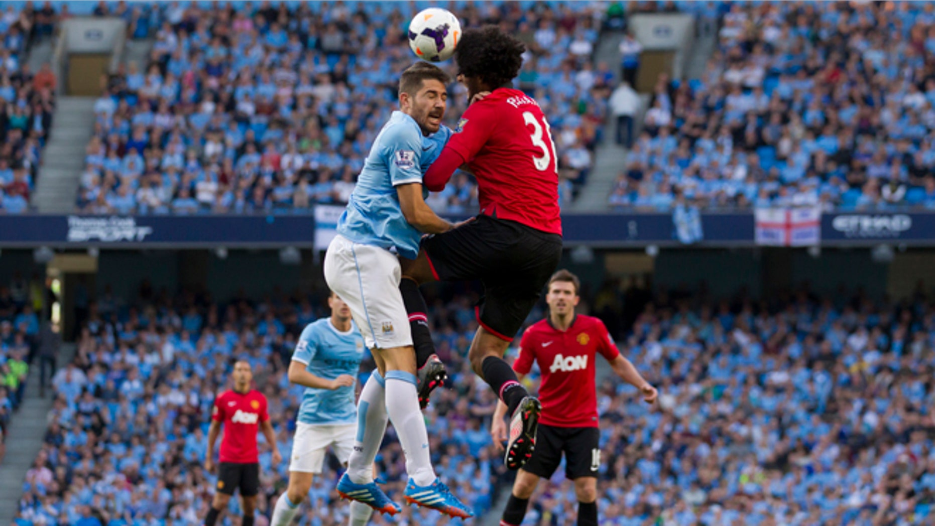 Manchester City's Aleksander Kolarov, centre left, jumps for the ball against Manchester United's Marouane Fellaini during their English Premier League soccer match at the Etihad Stadium, Manchester, England, Sunday Sept. 22, 2013. (AP Photo/Jon Super)