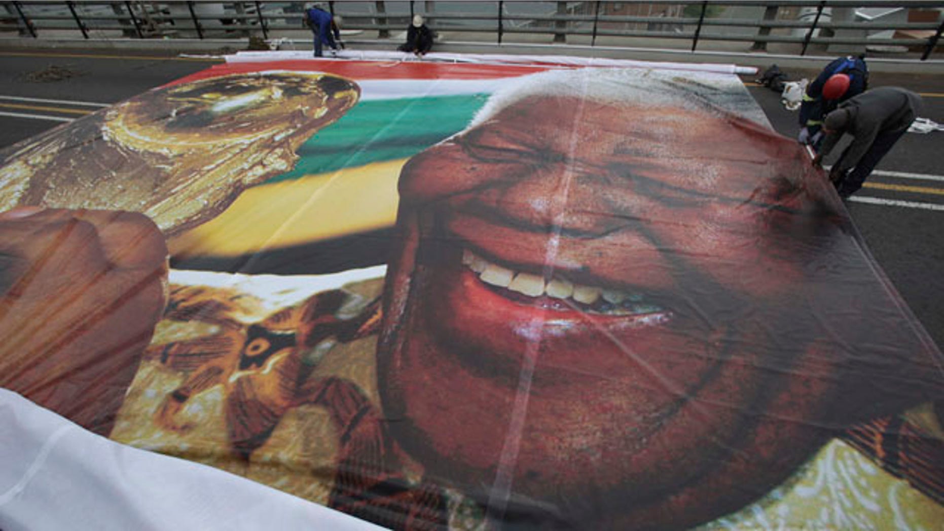 May 30: Workers prepare to hang an image of former President Nelson Mandela with the World Cup trophy on the Mandela bridge leading to downtown Johannesburg. (AP)