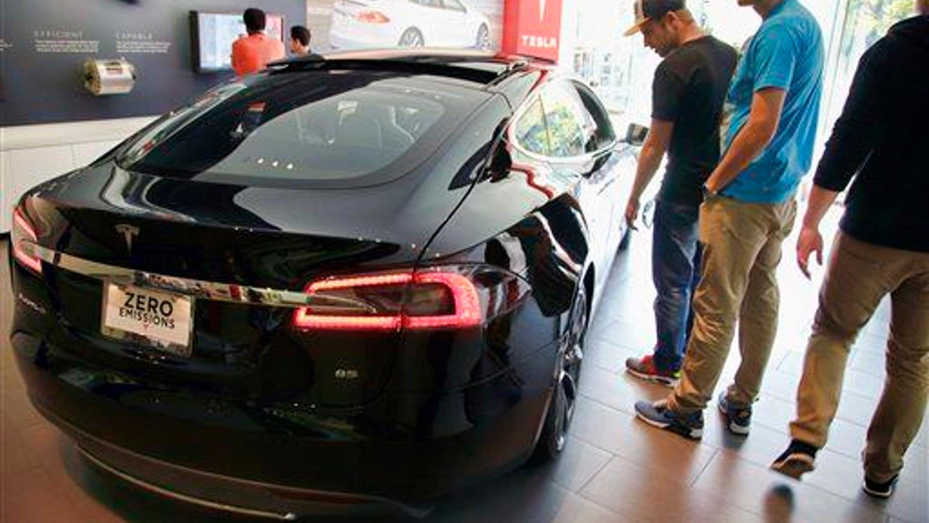 In this Saturday, Jan. 3, 2015 photo, people check out the Tesla model S at the Tesla showroom at the the Third Street Promenade in Santa Monica, Calif.