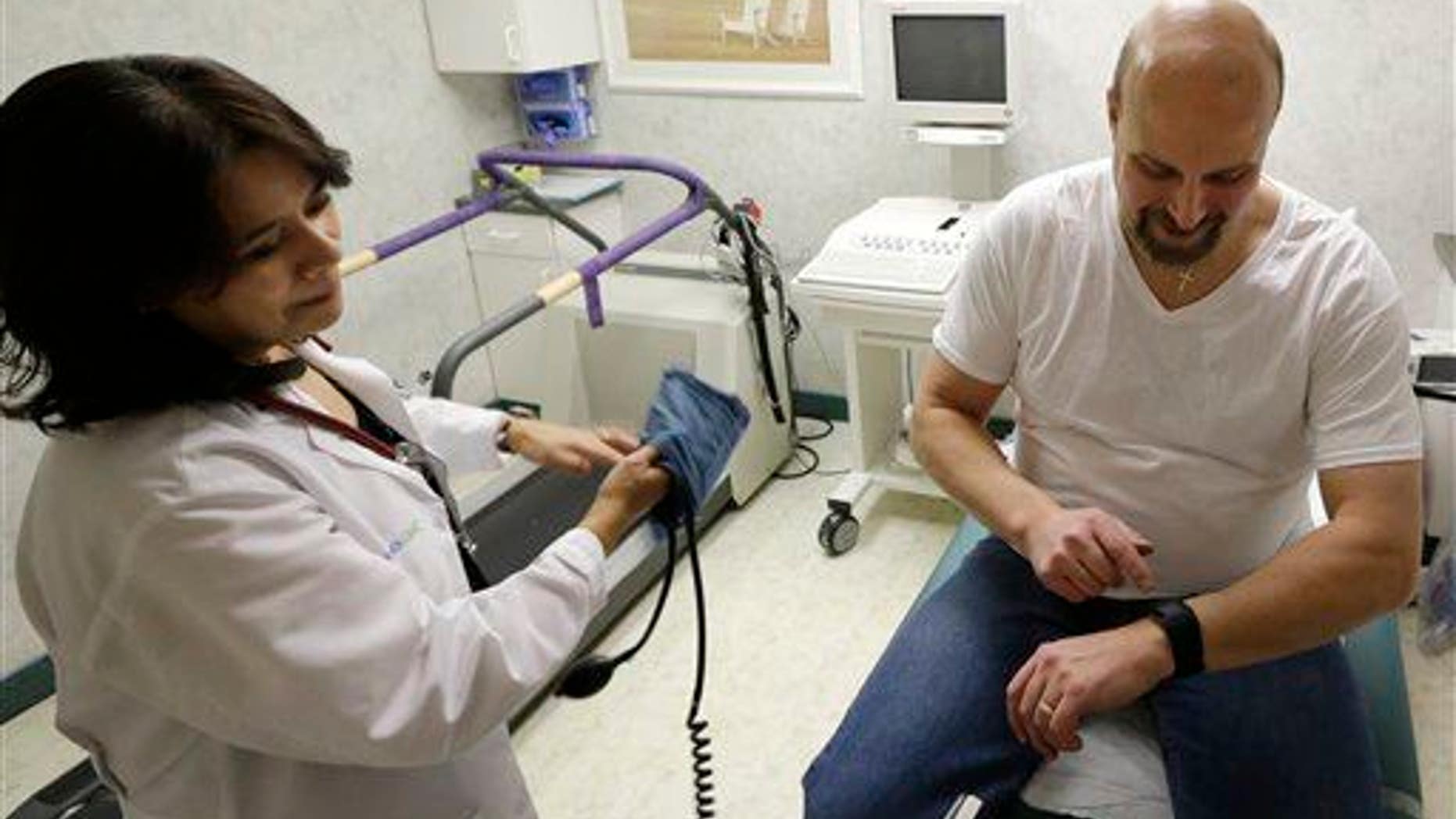 In this 2015 photo, a cardiologist looks on while her patient tracks data on a Fitbit Surge synchronized to hospital monitoring equipment.