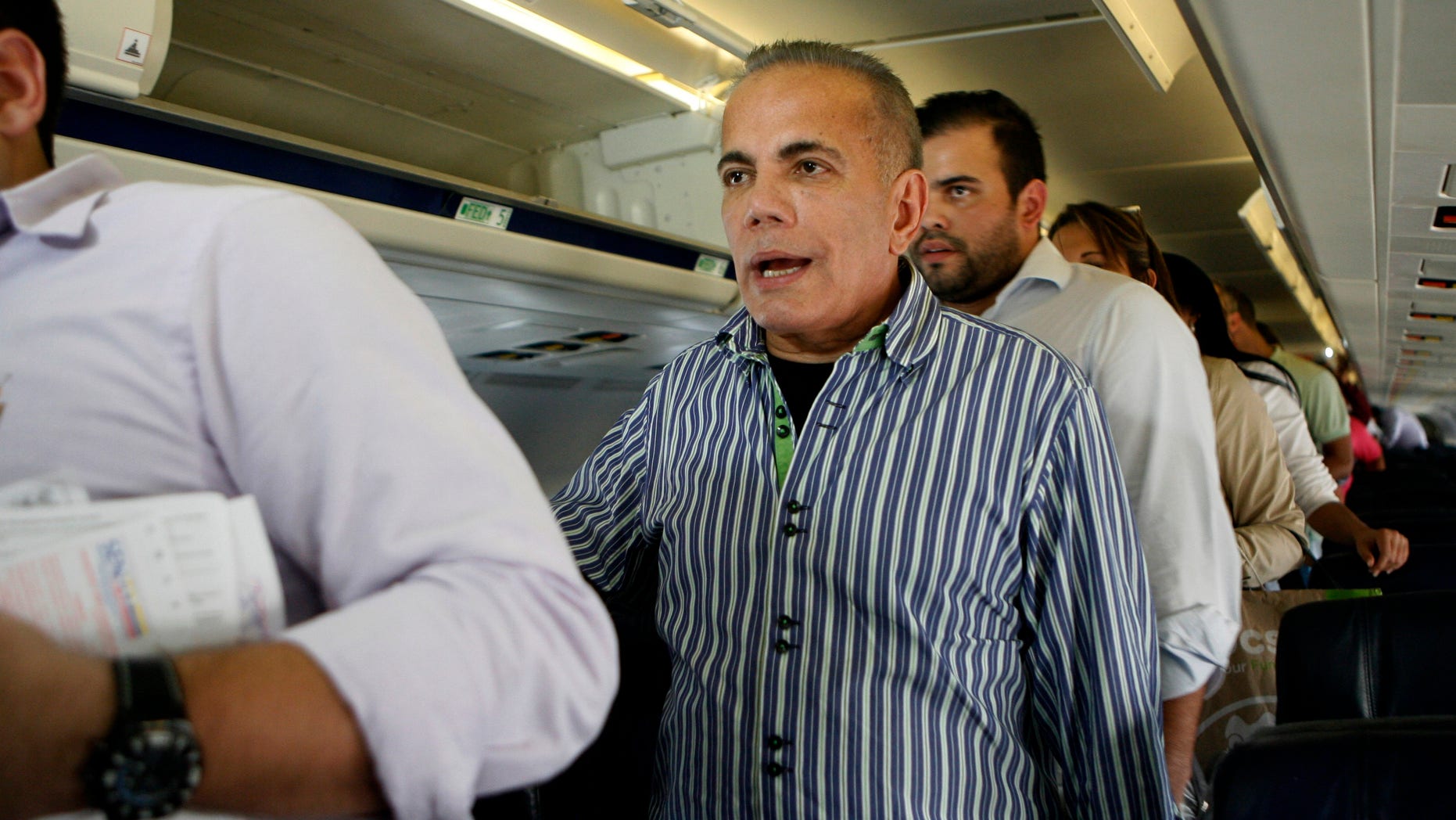 Venezuelan opposition leader Manuel Rosales, center, stand as he waits to leave a plane after it landed at La Chinita airport in Maracaibo, Venezuela, Thursday, Oct. 15, 2015. Rosales a former governor, who had been living in exile since 2009, was arrested when he returned to Venezuela and is expected to appear in a Caracas court later in the day. Rosales ran for president in 2006 and lost to Hugo Chavez. (AP Photo/Jhair Torres)