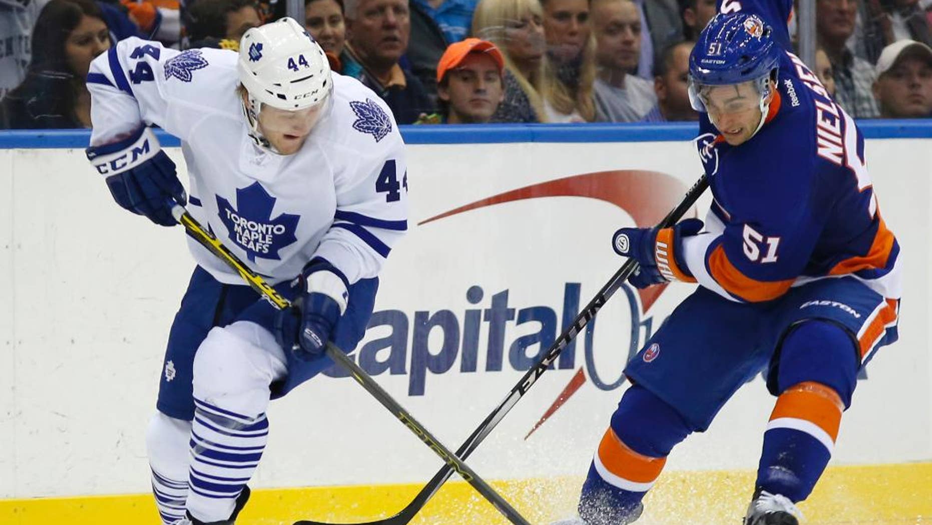 Toronto Maple Leafs defenseman Morgan Rielly (44) and New York Islanders center Frans Nielsen (51), of Denmark, compete for control of the puck during the second period of an NHL hockey game in Uniondale, N.Y., Tuesday, Oct. 21, 2014. (AP Photo/Kathy Willens)